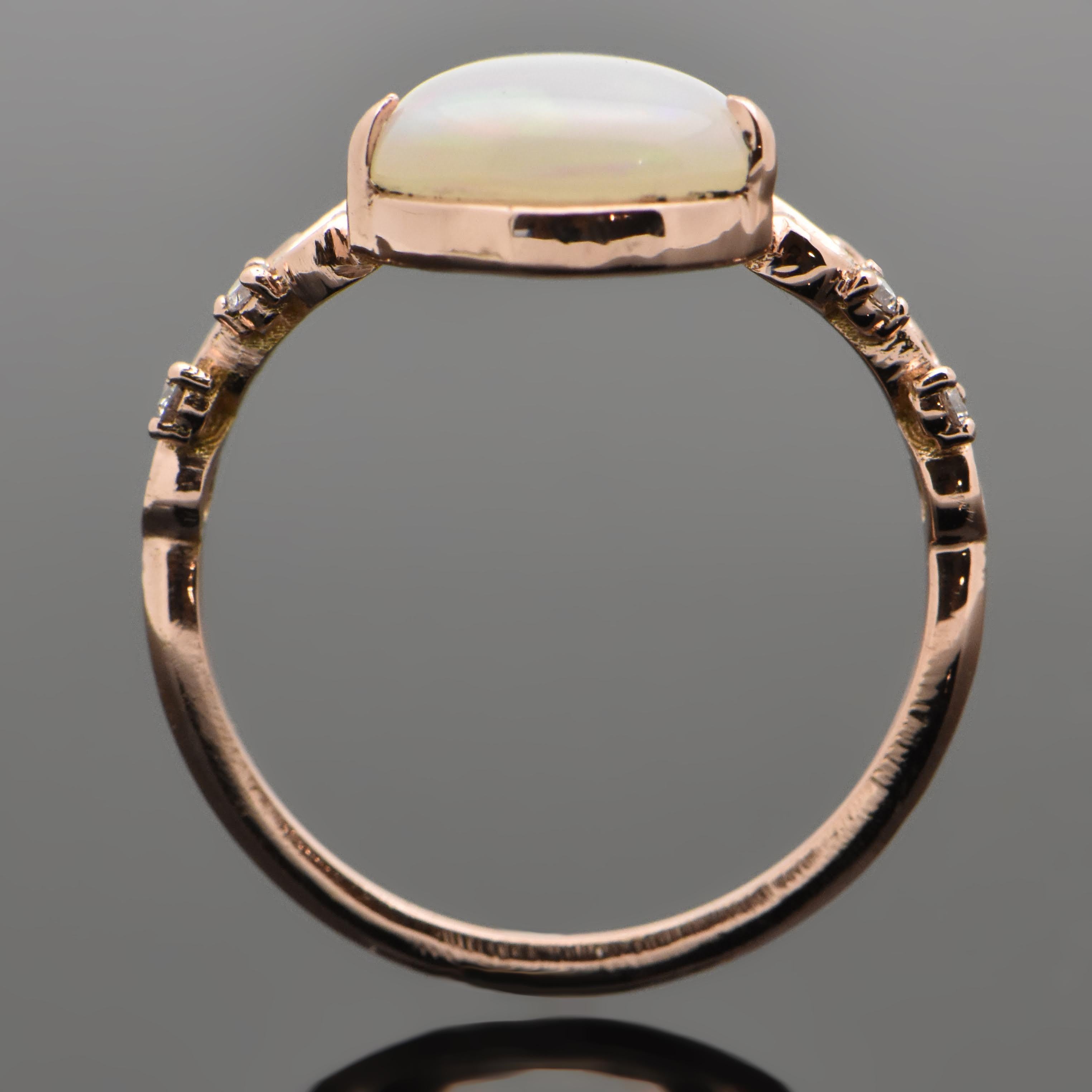A 14kt rose gold Ethiopian pear shaped opal with an estimated weight of 1.36ct featuring a delicately carved scroll design and accent diamonds. Estimated weight of gold 1.65 gr. 

We will size it for you.