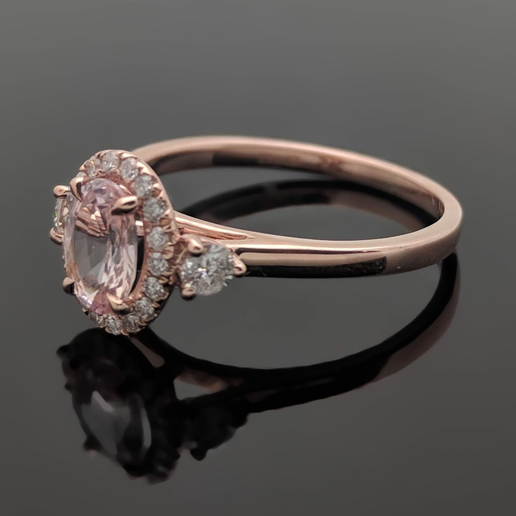 This 14kt rose gold ring is set with a pink sapphire estimated weight of 0.78ct and 4 claw prongs. The setting features a halo of diamonds as well as two side diamonds with an estimated 0.28cttw. Estimated weight of gold is 2 gr. 

We will size it