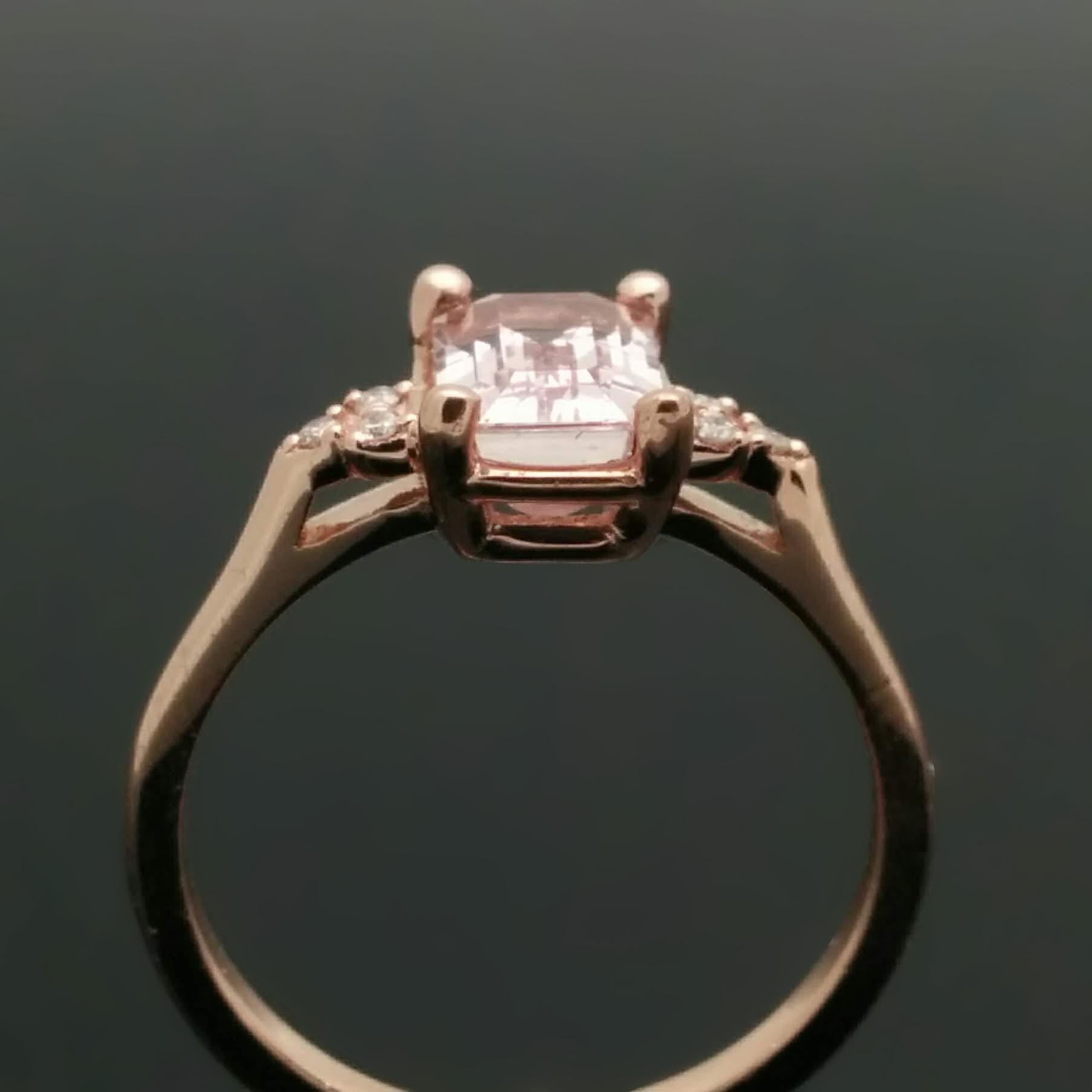 A 14kt rose gold ring set with a spectacular pink, emerald-cut sapphire estimated at 1.92ct. Each shoulder features 3 diamonds with an 0.02 cttw. Estimated weight of gold is 2 gr. 

We will size it for you.


