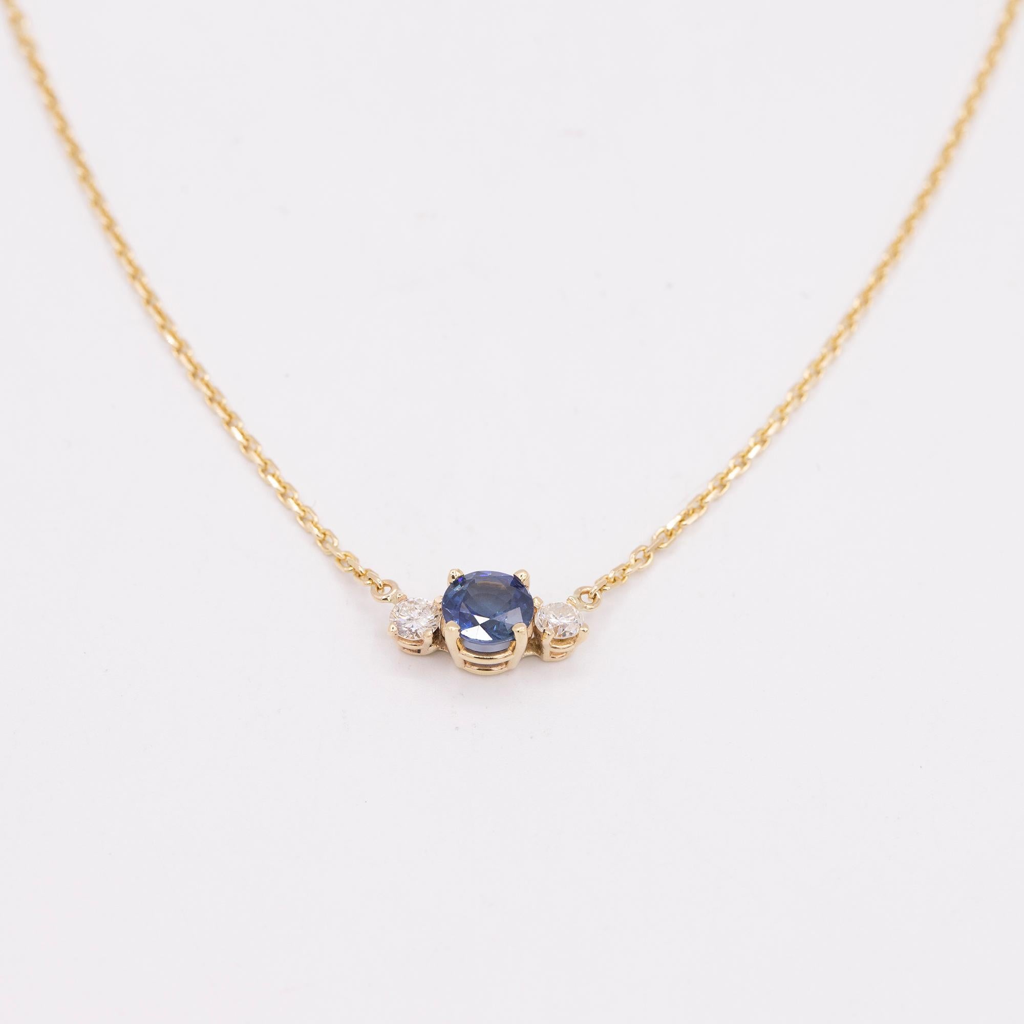 14kt yellow gold necklace with a center blue sapphire and two side diamonds. The sapphire weighs 1.40 carats flanked by two round brilliant cut diamonds weighing .44 carats in total weight. All stones are prong set on an 18