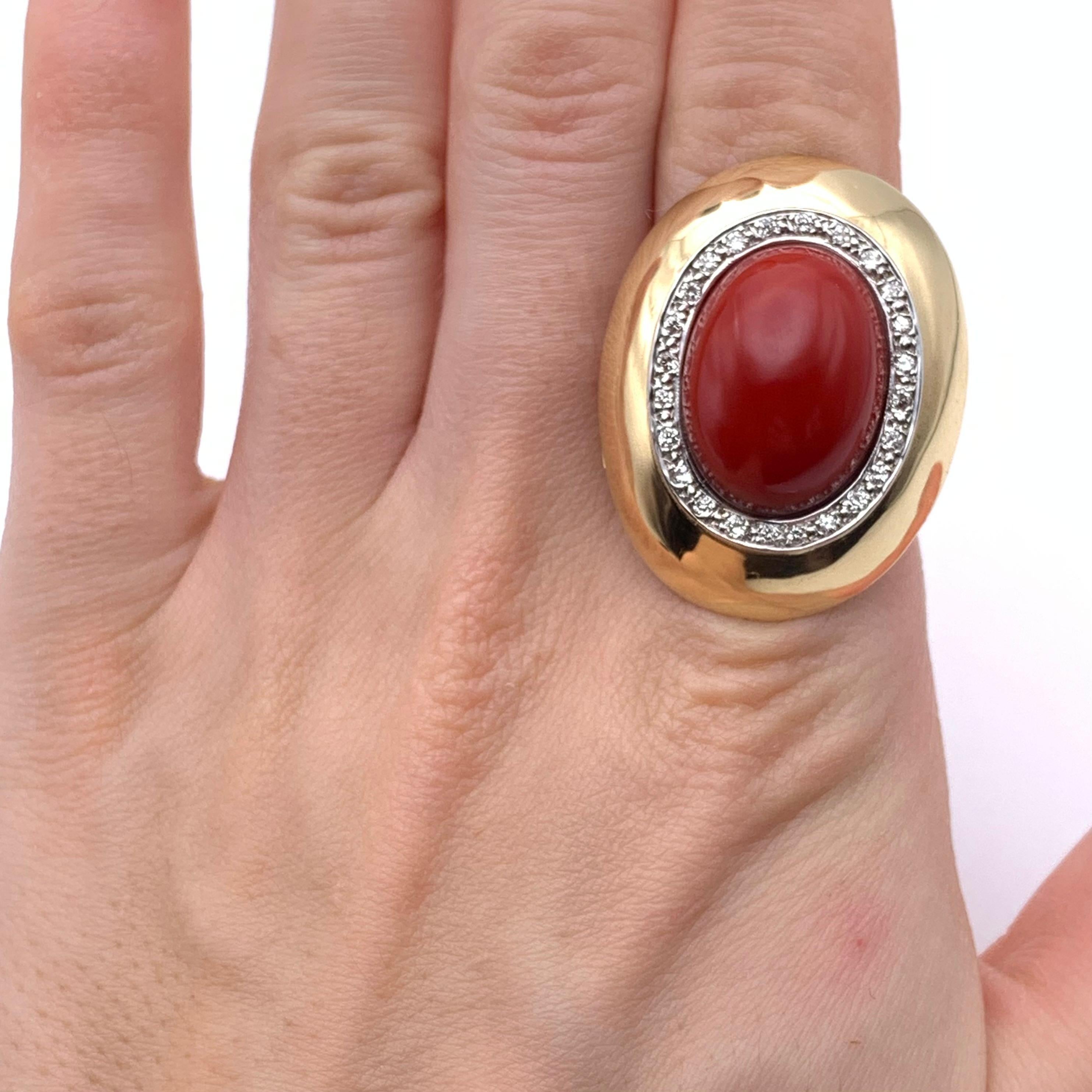 Dieser fabelhafte Vintage-Ring besteht aus 14-karätigem Gelbgold mit einem Hauch von Weißgold, um den Diamantenhalo hervorzuheben. Der Mittelstein ist ein Stück sardischer ochsenblutfarbener Koralle im Cabochon-Schliff. Der Edelstein misst 19,5 x