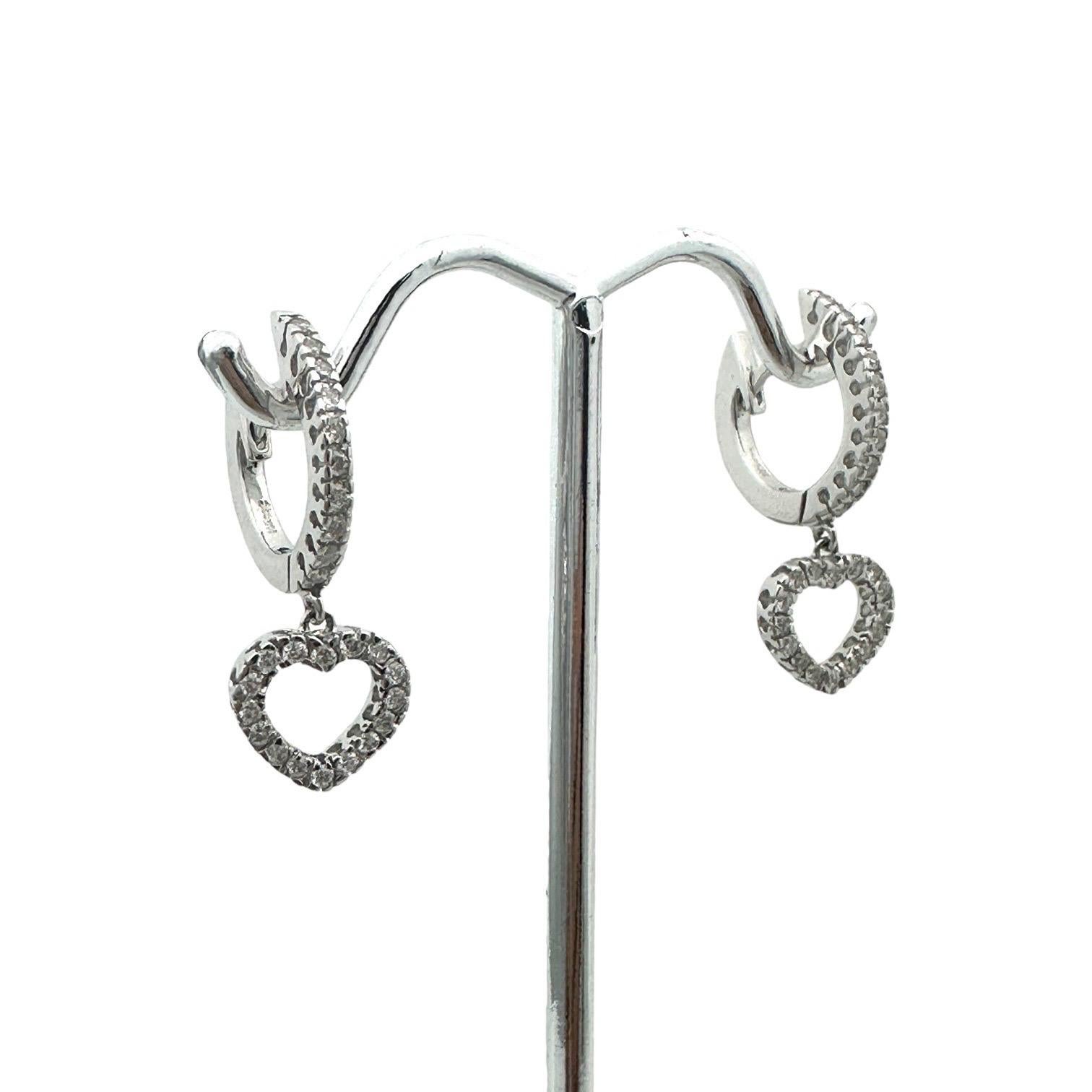 Fabriquées en or blanc 14 carats, ces boucles d'oreilles Heart huggy sont ornées de diamants brillants d'un poids total de 0,95 carat. Chaque boucle d'oreille mesure un pouce de long au total, ce qui garantit des pièces durables et de bonne facture.