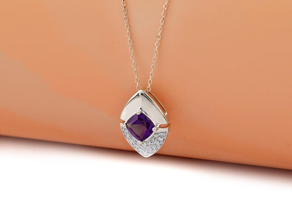 La suspension présente un design géométrique moderne et saisissant, semblable à celui d'un bouclier. L'améthyste est placée en évidence au centre, dans un sertissage sûr, entouré par le travail du métal. La partie inférieure du modèle présente des