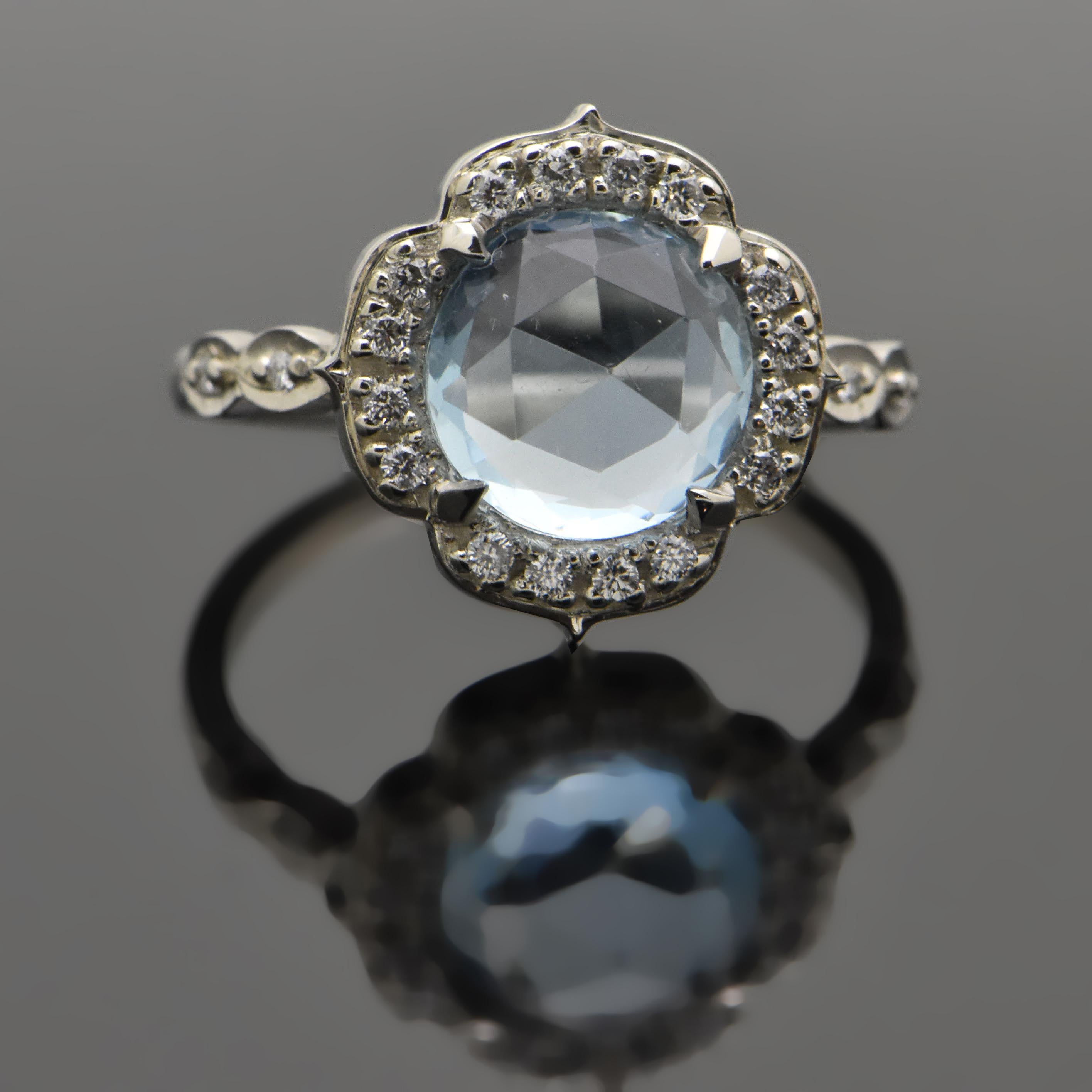 14kt White Gold Aquamarine and Diamonds Ring. This ring features a rose cut aquamarine with a scalloped-edge halo lined with diamonds and diamond accents on the shoulders. 

This item is a custom order only. Price is for the ring setting only. The