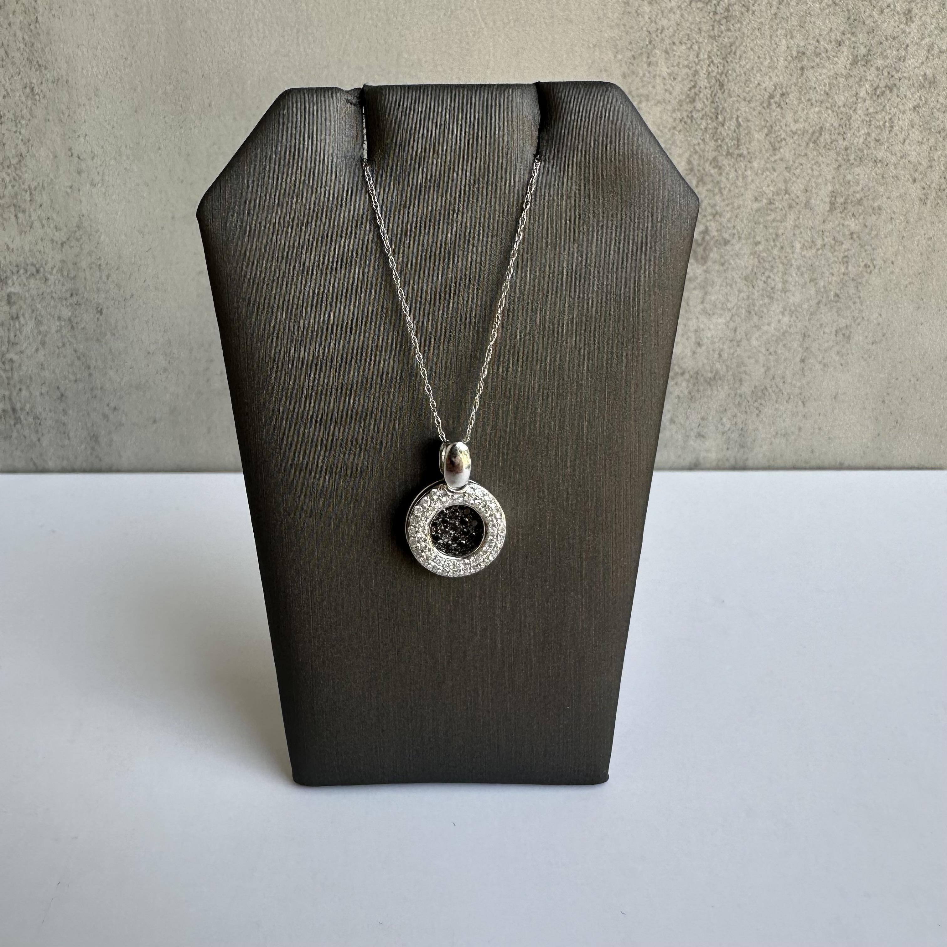 Aggiungi un tocco di moderna eleganza alla tua collezione di gioielli con questa squisita collana di diamanti bianchi e neri in oro bianco 14kt. Con 0,75 carati di diamanti naturali GH SI, questa collana mette in mostra un sorprendente pendente