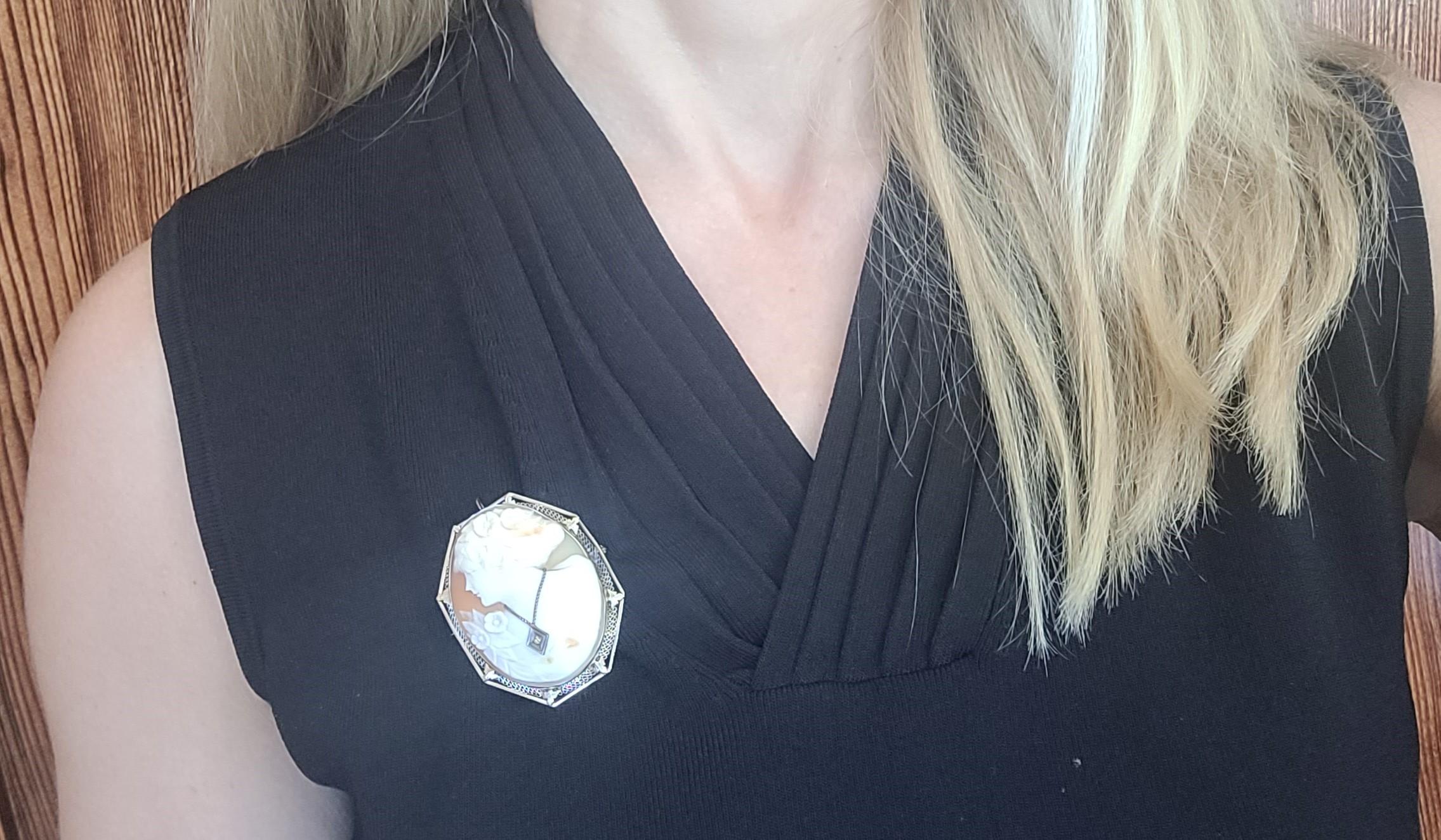 Embrace the elegance of this stunning Victorian Era 14kt white gold cameo pin/pendant, measuring 19 x 15 x 10 mm. Adorned with an octagonal shell cameo showcasing a lady adorned with flowers in her hair, complemented by a white gold single-cut
