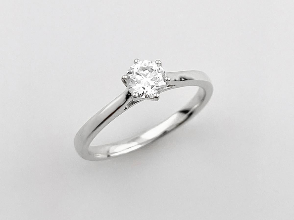 Este anillo solitario clásico presenta un diseño atemporal y elegante, ideal para un anillo de compromiso o un regalo significativo. Presenta un único diamante brillante de talla redonda sujeto firmemente en un engaste 