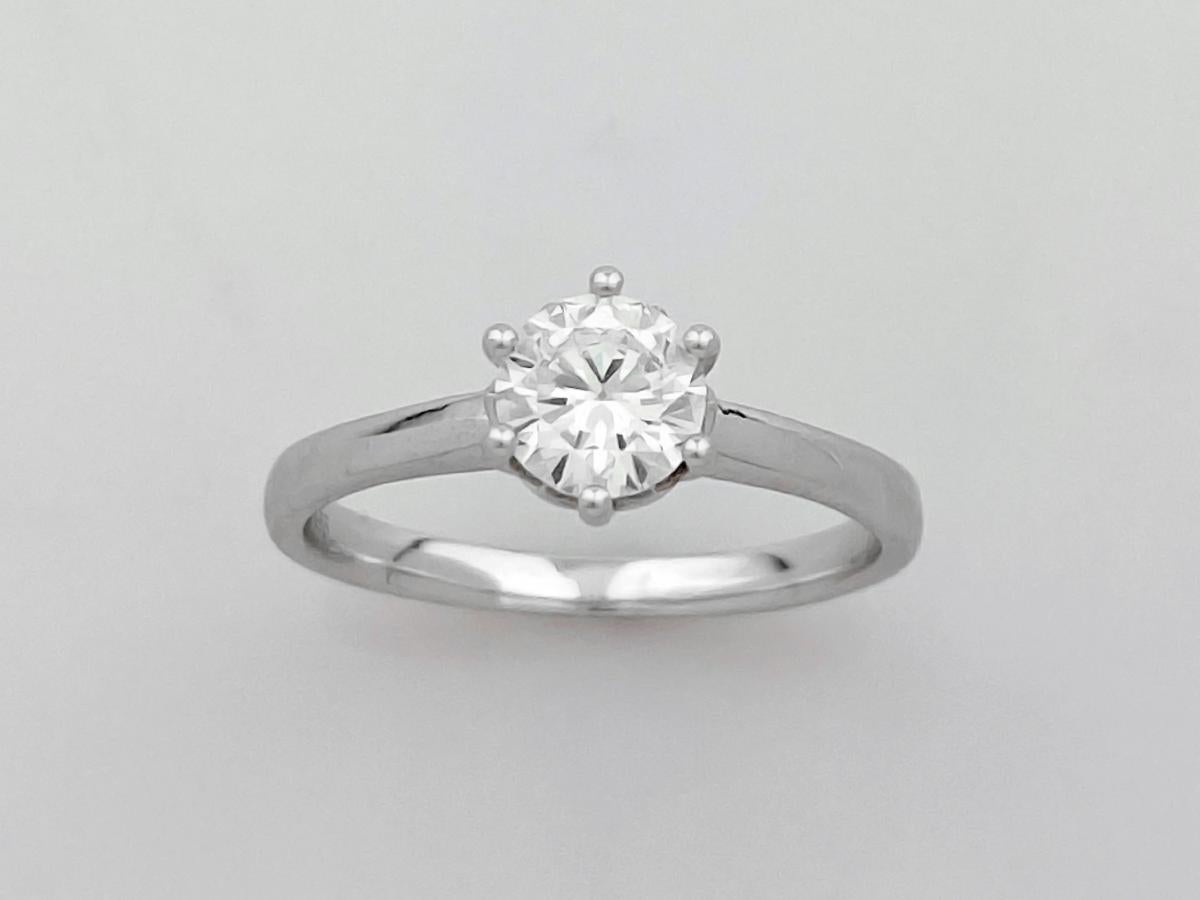 Cette bague solitaire classique présente un design intemporel et élégant, idéal pour une bague de fiançailles ou un cadeau important. Elle est ornée d'un seul diamant brillant de taille ronde, solidement maintenu dans une monture à six griffes de