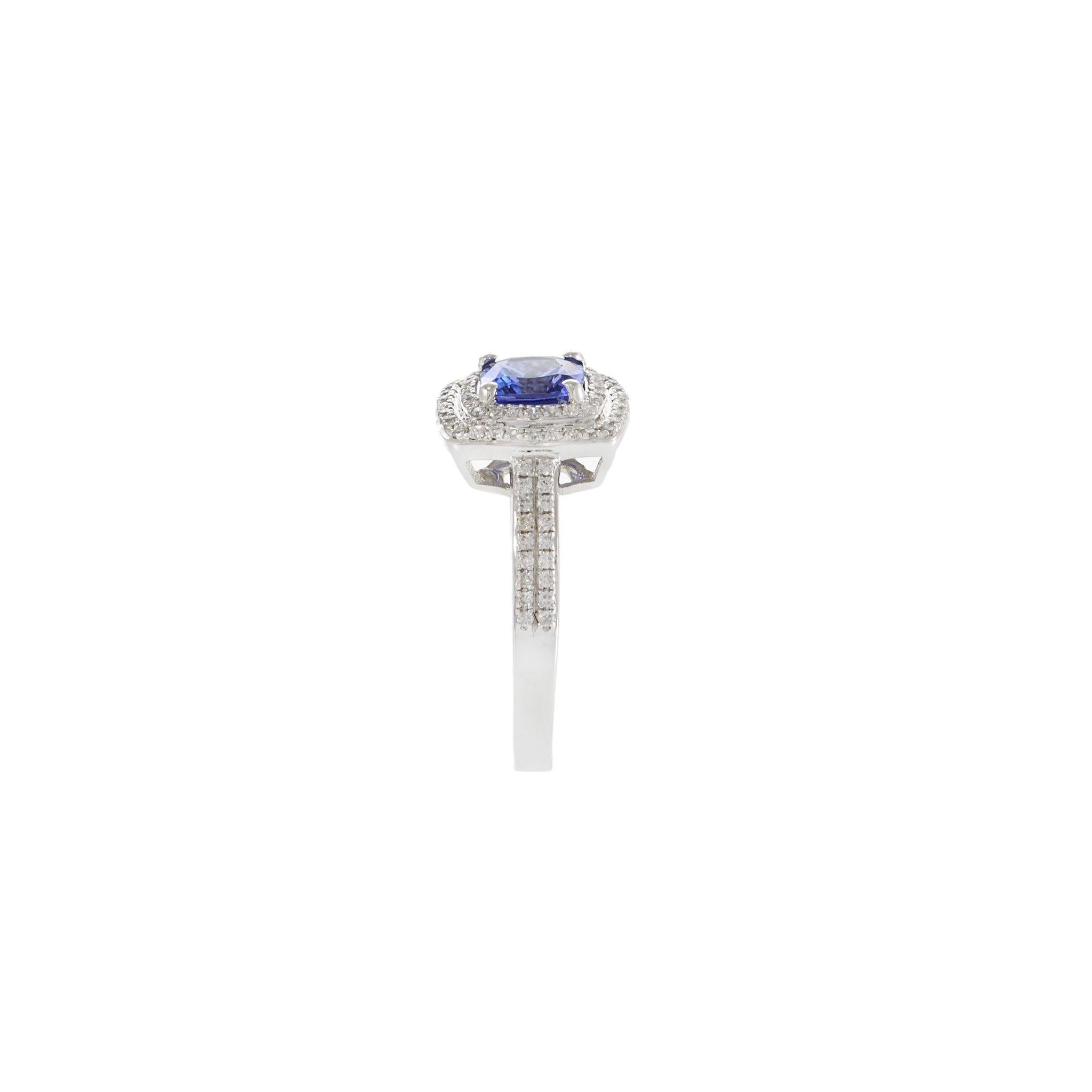 A captivating blend of color and brilliance, this elegant ring features a cushion-cut tanzanite center stone weighing 1.30 carats, nestled within a double halo of shimmering round cut diamonds. Set in luminous 14KT white gold, the ring’s split shank