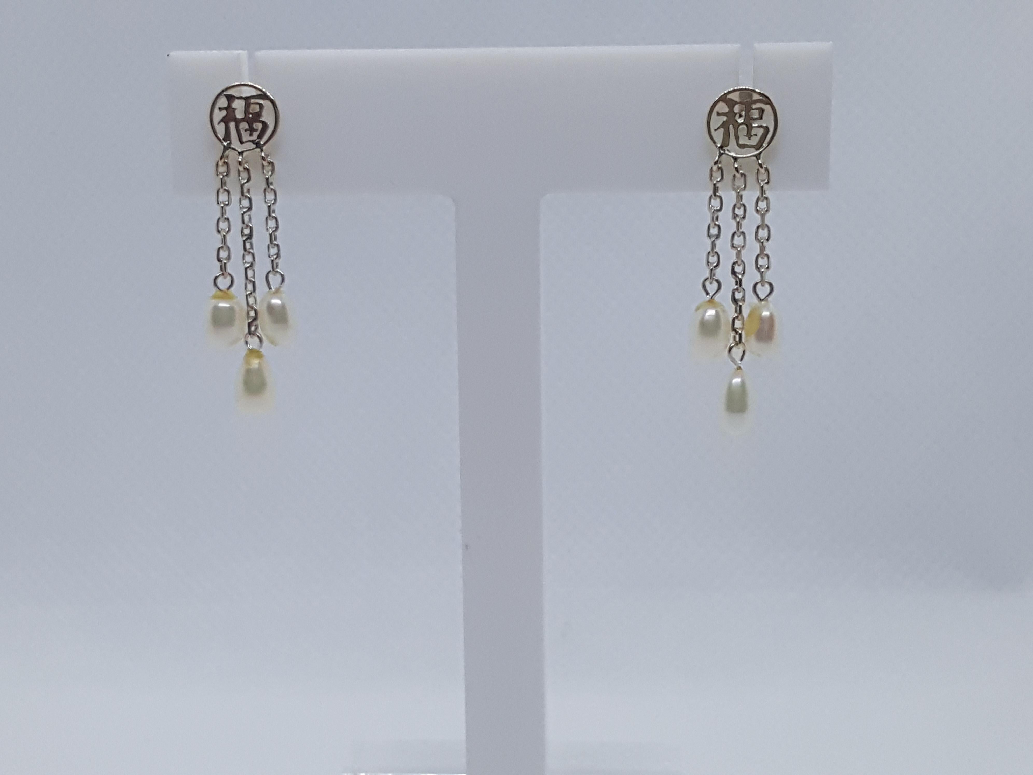 Unique pair of 14kt white gold friction post earrings with a round Asian design that's 6.7mm in diameter from which three graduated strands of link chain hold oval-shaped fine freshwater pearls. The total length of each earring is 1.25 inches both