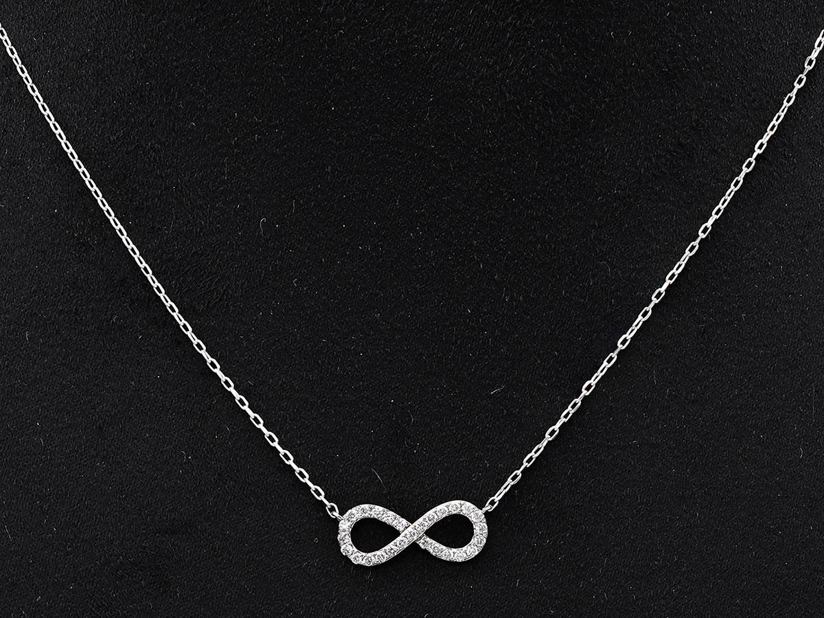 Le pendentif présente l'élégant symbole du huit couché à l'horizontale, ou lemniscate, qui représente quelque chose qui n'a ni début ni fin. La surface du symbole est recouverte de petits diamants ronds sertis en pavé qui maximisent l'éclat et la