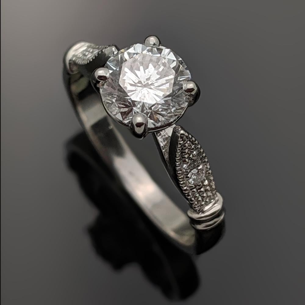 14kt White Gold Diamonds Ring. This ring features a round brilliant cut diamond in 4 prongs and milgrain raised shoulders with 2 accent diamonds. 

This item is a custom order only. Price is for the ring setting only. The stone will be priced