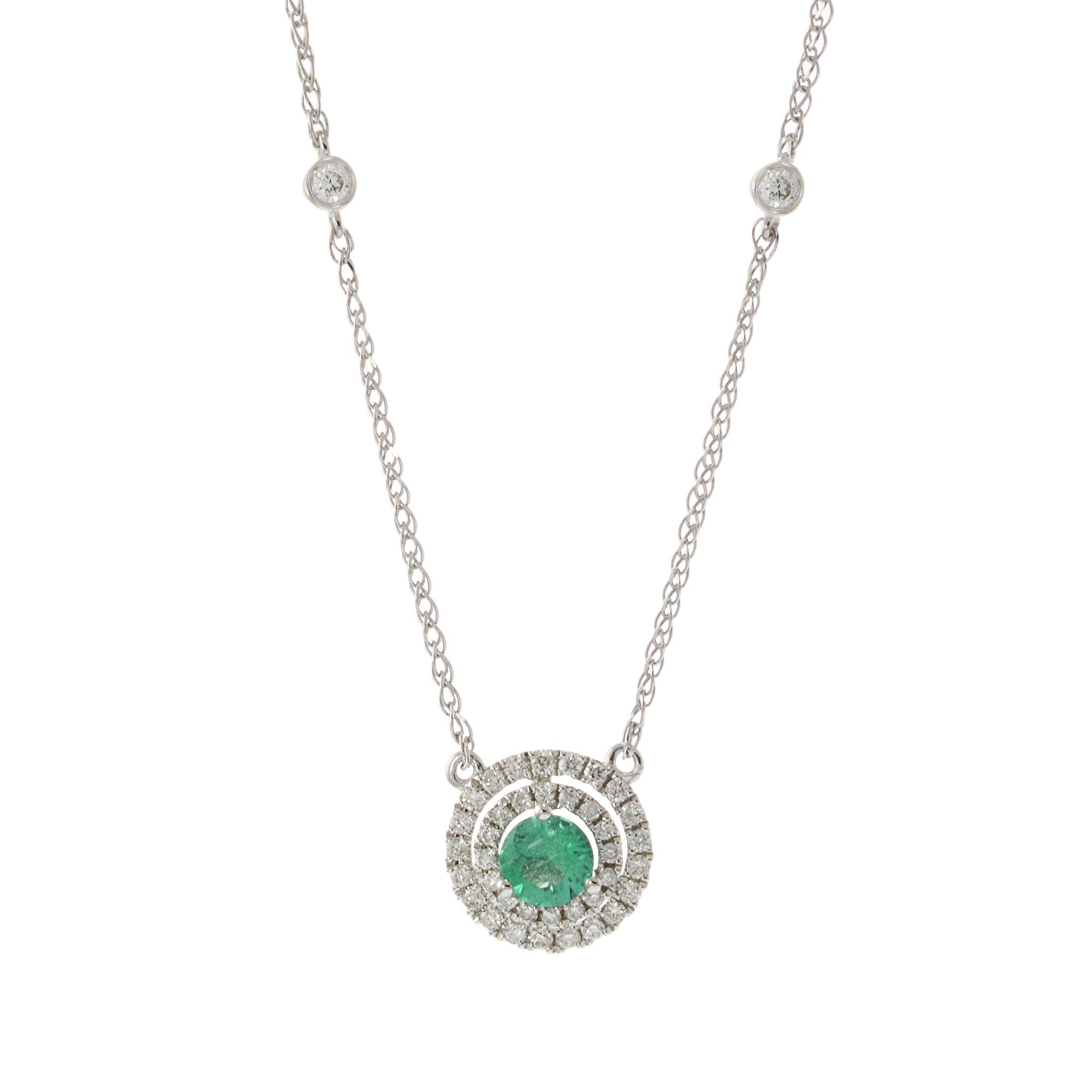This elegant necklace features a 0.29 carat genuine round cut emerald, beautifully set in 14KT white gold. The emerald is surrounded by a halo of 0.24 carats of round cut diamonds, adding a sparkling frame that enhances the gemstone's vibrant green