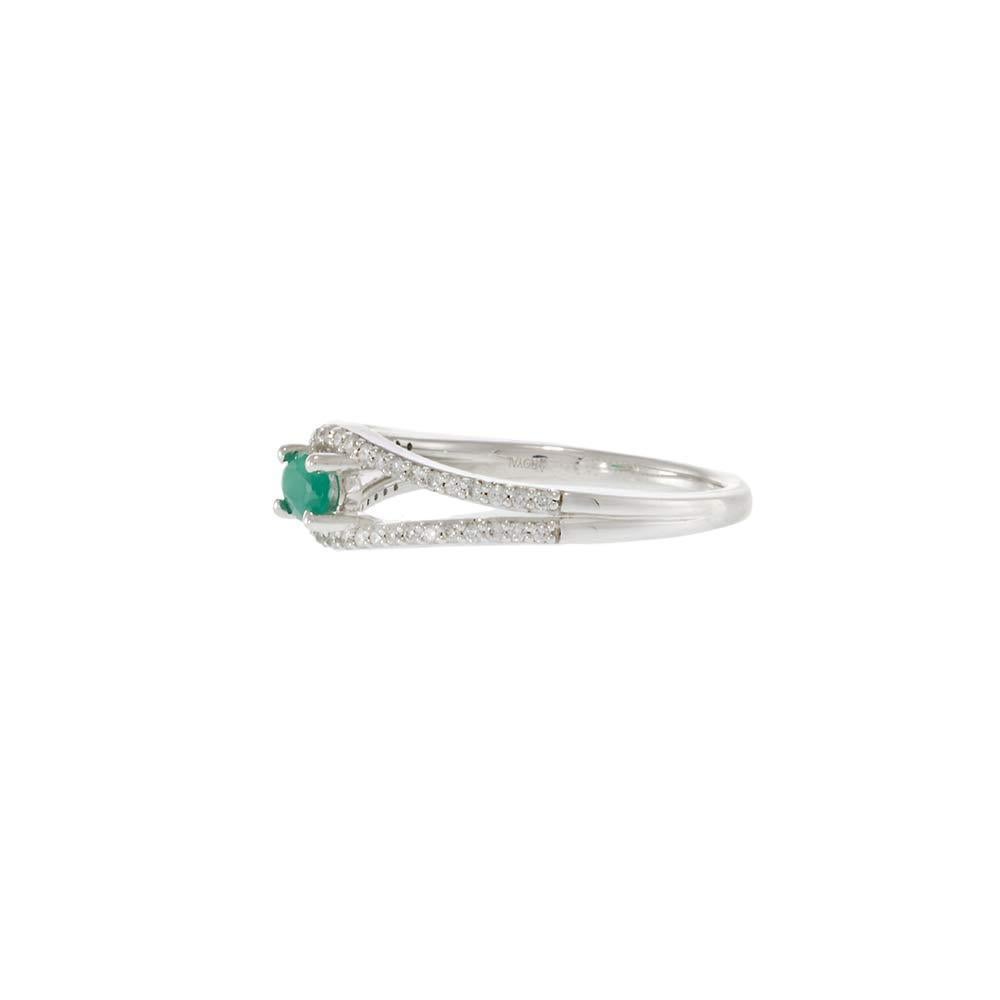 Crafted in luminous 14KT white gold, this elegant ring showcases an oval-cut emerald at the center, framed by a split-shank design adorned with round brilliant cut diamonds. The vivid green emerald is accentuated by 0.20 carats of sparkling