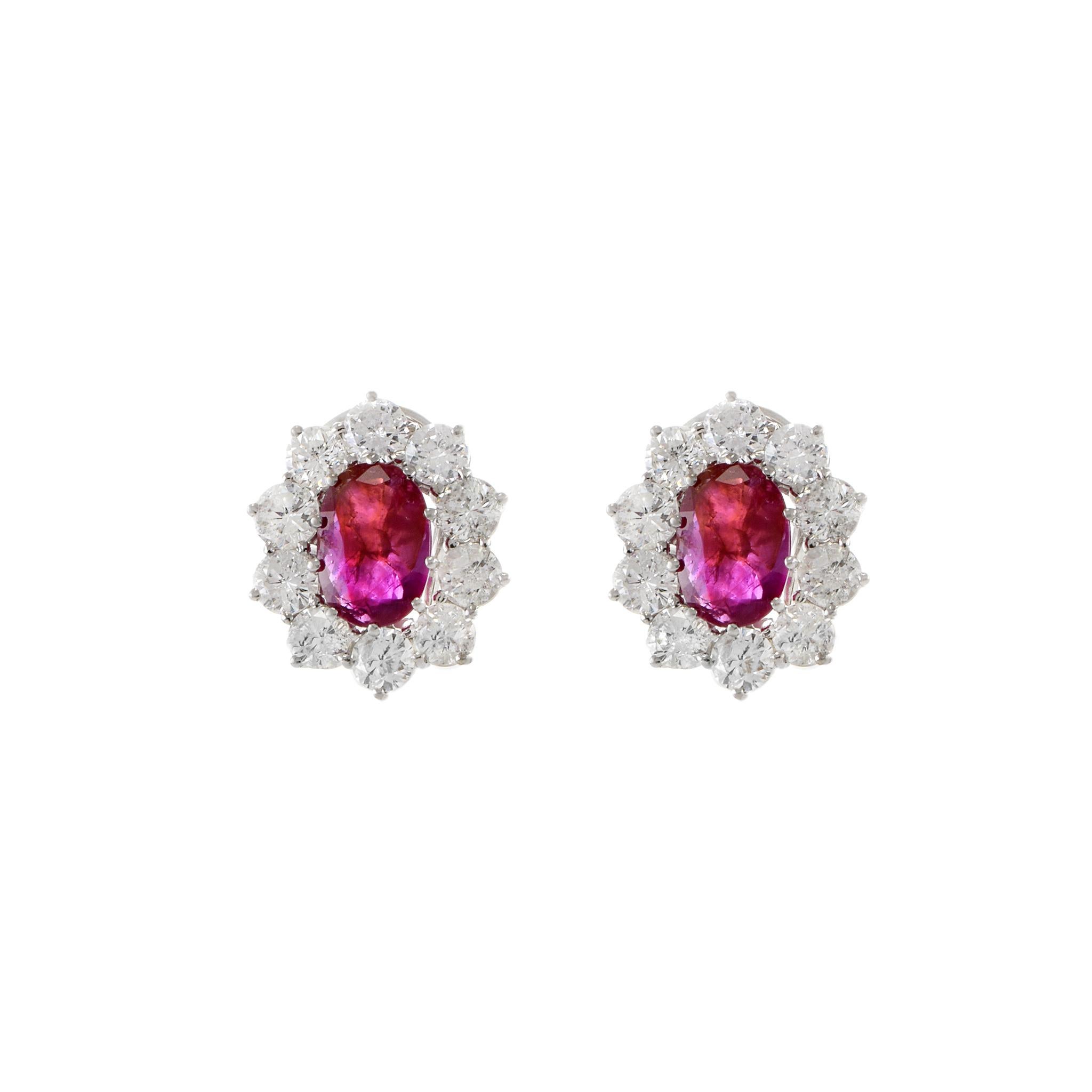 14KT white gold earrings featuring 4.29CT-TW oval Burmese Rubies surrounded by 4.10CT-TW H-I Color SI1-I1 Clarity round brilliant cut diamonds. These luxurious earrings feature genuine precious stones expertly set in quality 14KT white gold,