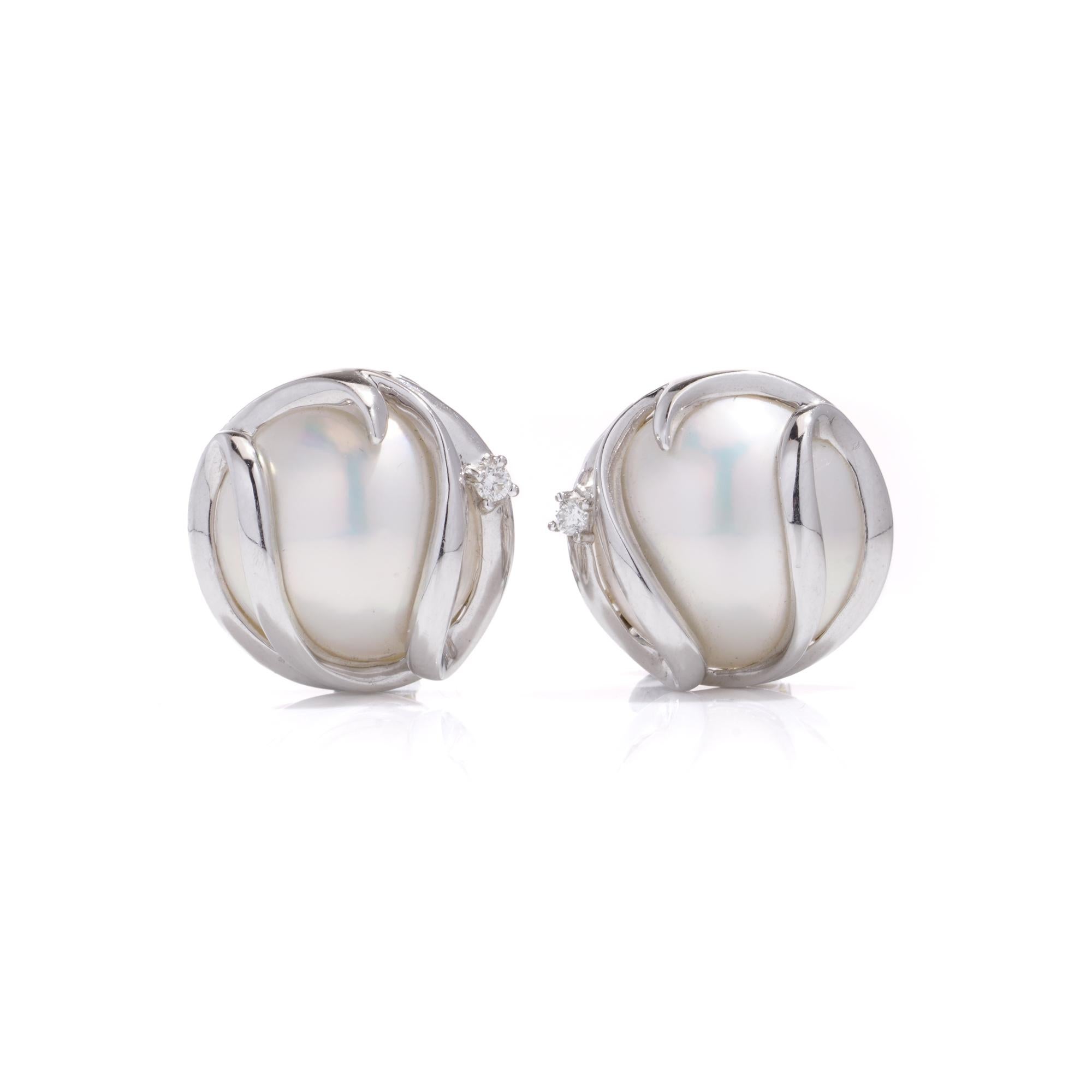 Vintage 14kt white gold pair of Mabe pearl and diamond earrings. 
Bezel set. 
Made in 1990s 
X - ray tested positive for 14kt gold. 

Cultured Mabe pearls - 
Quantity: 2 
Size: 14 mm
Pearl Oyster: Pinctada Maxima
Pearl bodycolour: White 
Pearl