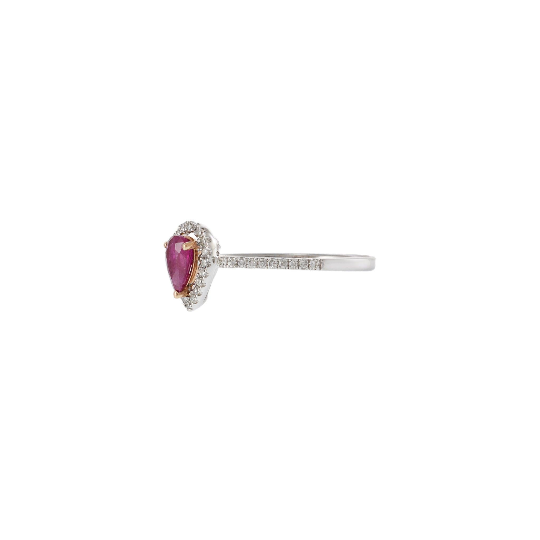 This elegant 14KT white gold ring features a vibrant 0.50 carat pear-shaped ruby, highlighted by a delicate halo of 0.15 carats of round cut diamonds. The ruby is prong set in 14KT yellow gold, adding a touch of warmth to the cool tones of the white