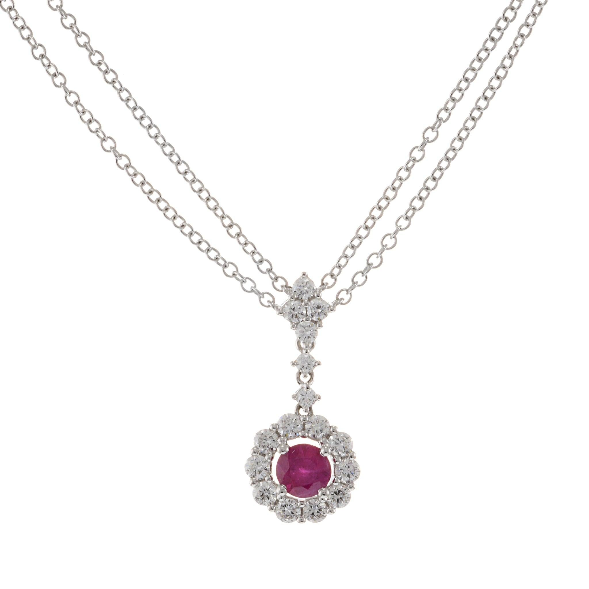 Questa elegante collana presenta un rubino singolo a taglio rotondo al centro, del peso di 0,38 carati, circondato da 0,47 carati di diamanti a taglio rotondo di purezza VS. Il rubino e i diamanti sono incastonati in un fiore a grappolo, realizzato