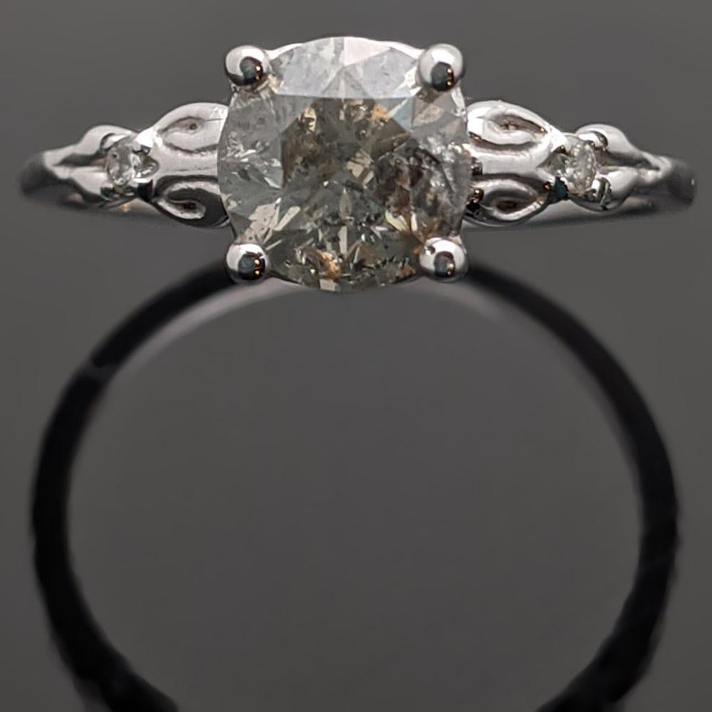 A 14kt white gold ring featuring a salt & pepper center diamond and two accent diamonds with an estimated 1.04cttw. Estimated weight of gold is 2 gr. 
We will size it for you.