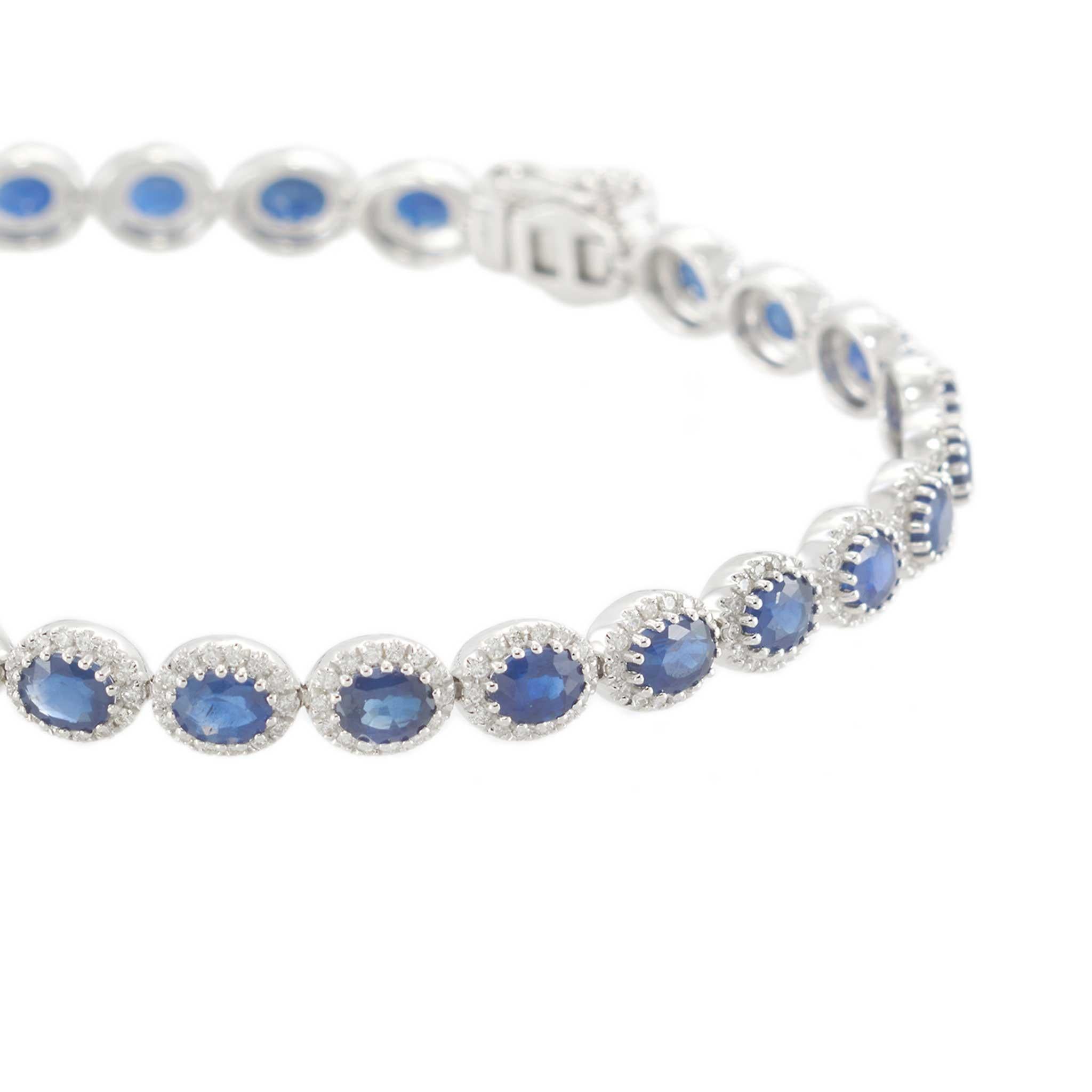 Crafted in luminous 14KT white gold, this elegant tennis bracelet features 7.20 carats of oval-cut blue sapphires, each framed in a sparkling halo of diamonds. The 1.20 carats of round brilliant diamonds (G-VS/SI) provide a refined shimmer that