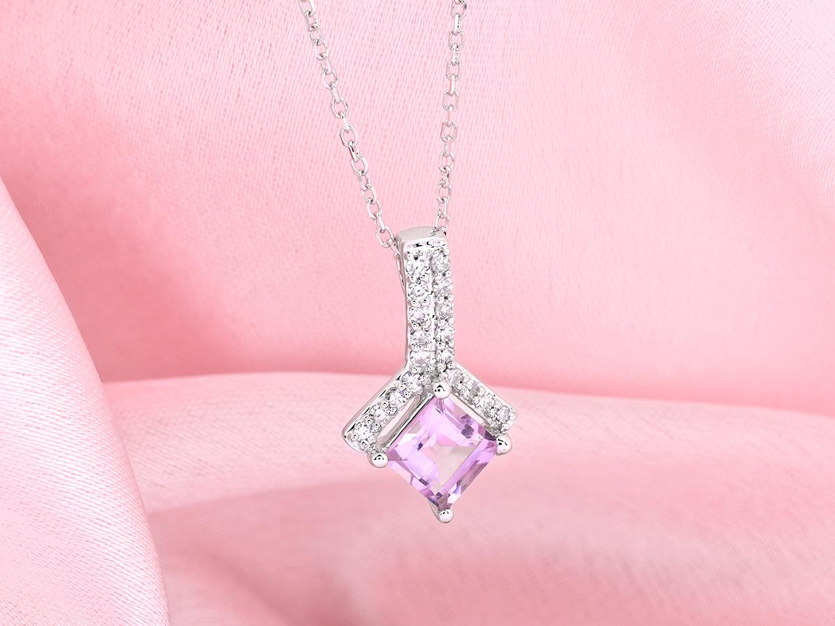 La suspension présente un design moderne et élégant en forme de goutte d'eau. Une améthyste carrée ou de taille princesse est sertie en évidence dans le bas, maintenue par des griffes en or. Au-dessus de l'améthyste se trouve une section en forme de