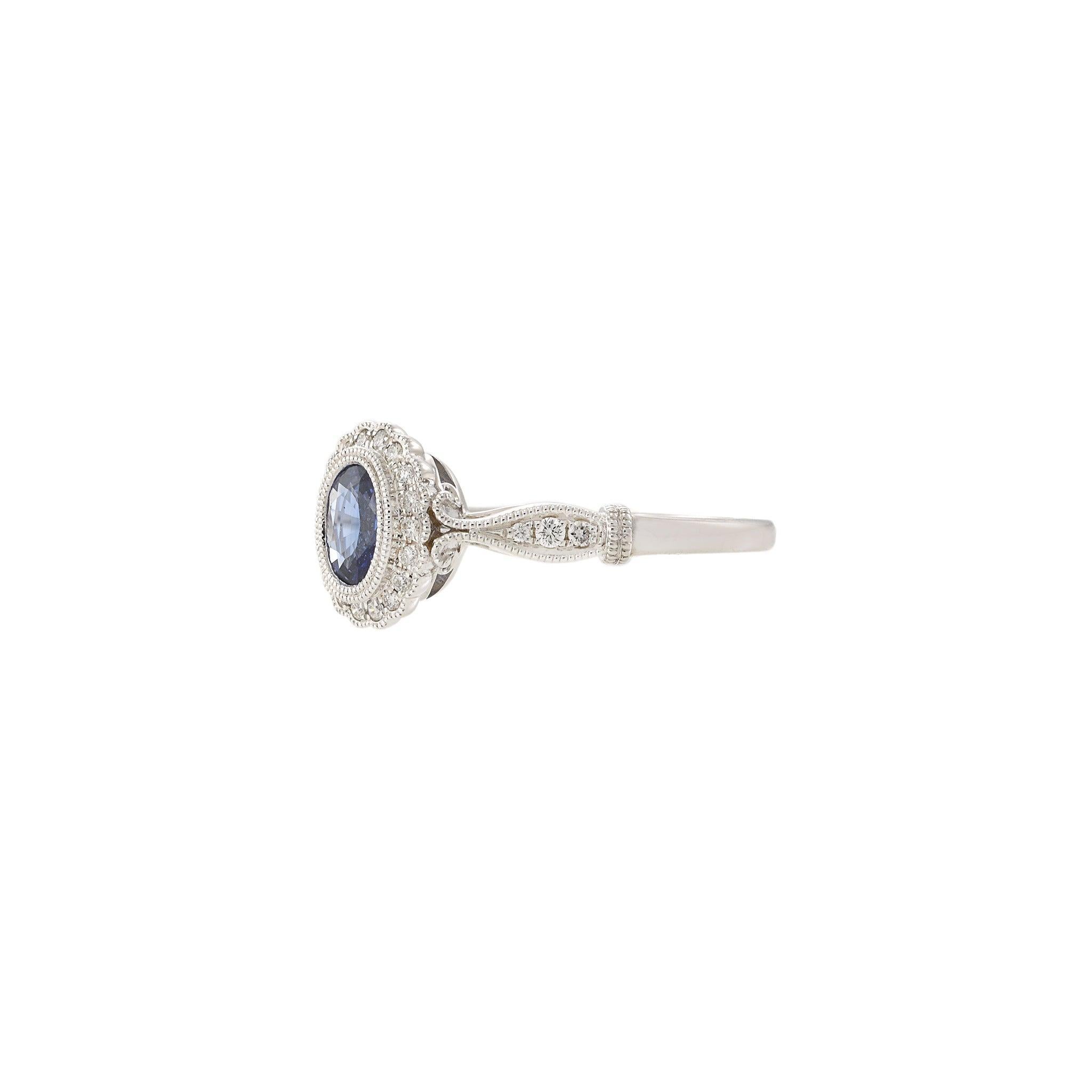 Delicately designed with vintage charm, this 14KT white gold ring features a rich oval-cut sapphire framed by a halo of round brilliant-cut diamonds. The milgrain detailing and intricate craftsmanship along the band add a timeless elegance