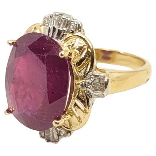 Questo bellissimo anello in oro giallo a 14 carati presenta uno splendido rubino ovale di 15 mm x 11 mm, circa 10 carati. Il rubino ha una vibrante tonalità rosso-violacea ed è trattato termicamente e riempito, mostrando alcune leggere abrasioni
