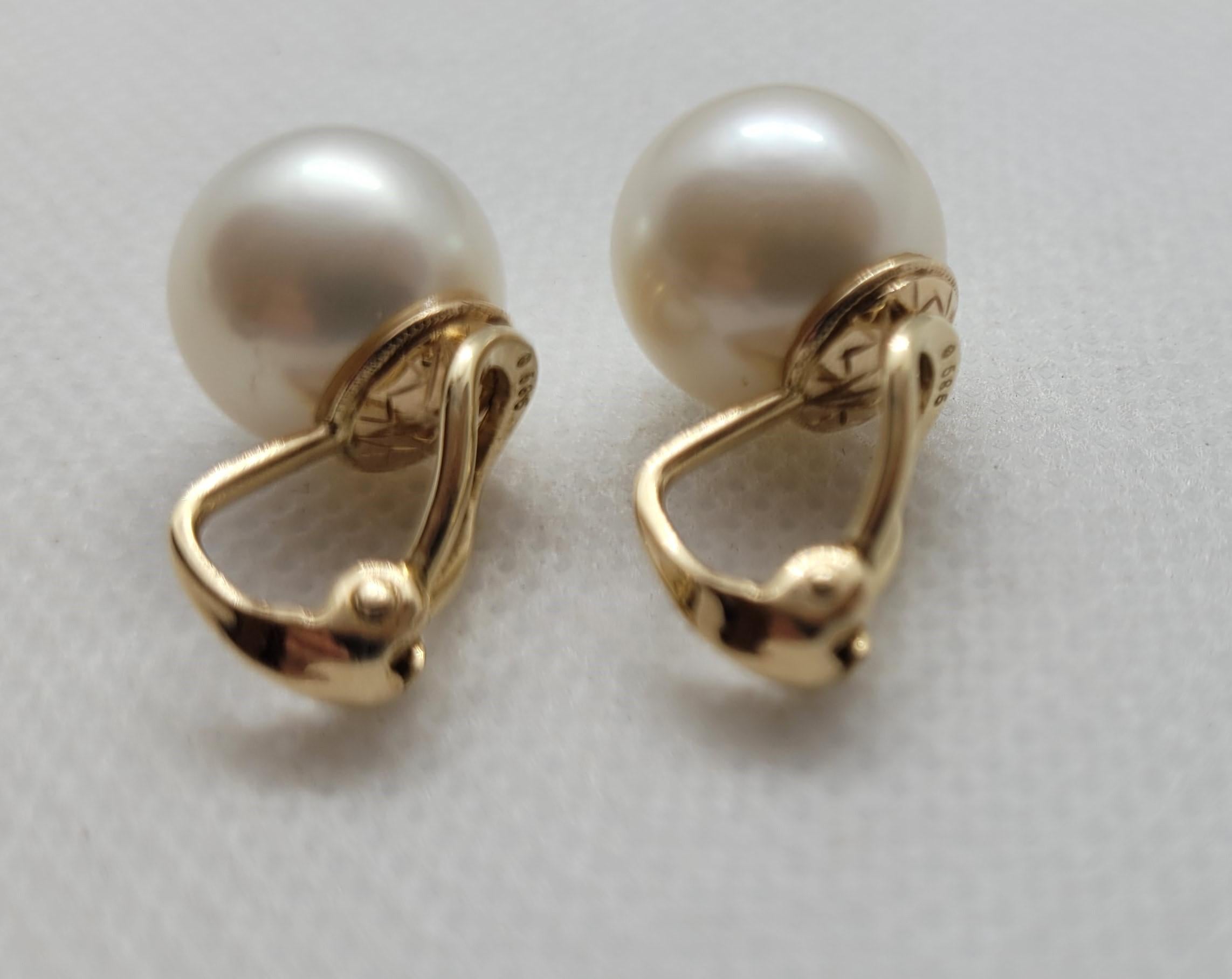 Questi squisiti orecchini a clip in oro giallo 14kt presentano due splendide perle coltivate bianche e grigie da 12,6 mm, dalla lucentezza brillante. Le perle si trovano elegantemente su una base finemente lavorata, che ne esalta la naturale