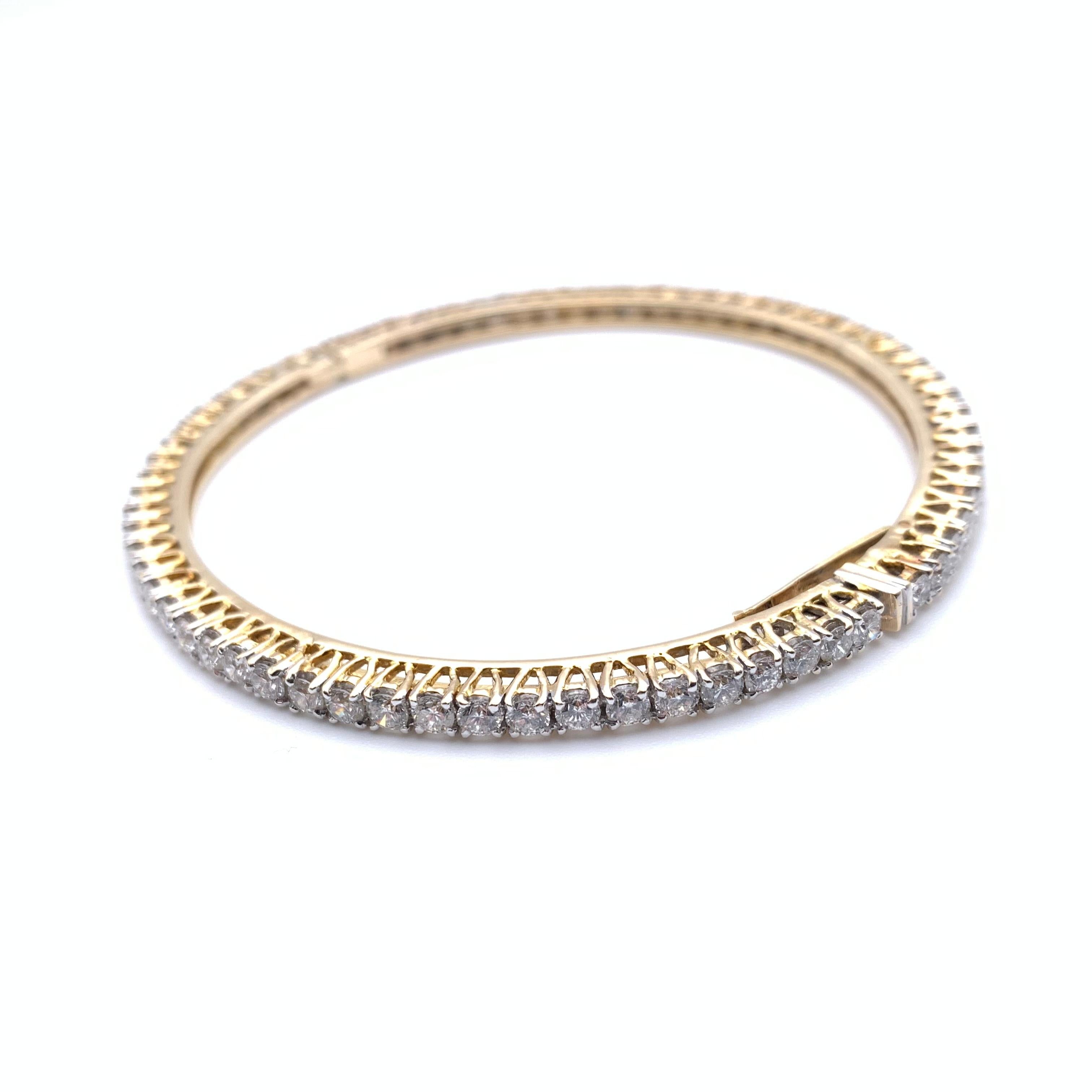 Ce bracelet classique fait partie de notre collection de succession. Il s'agit d'un bracelet circulaire à charnière en or jaune 14 carats. 70 diamants ronds naturels d'un poids total de 7,0 carats sont sertis à l'infini. Les diamants sont de pureté