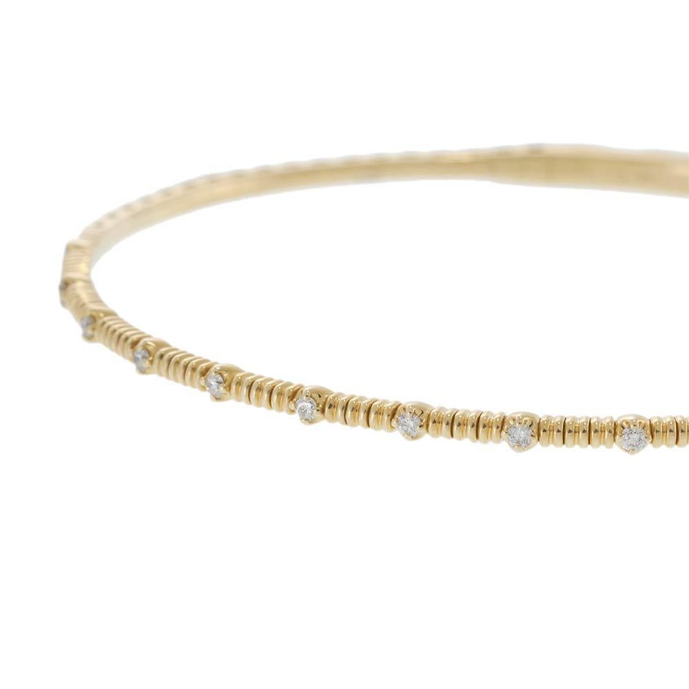 Elegant and minimal with a hint of sparkle, this 14KT yellow gold flex bangle features a series of bezel-set round diamonds in an alternating pattern. The flexible construction ensures a secure, comfortable fit that contours to the wrist. With a