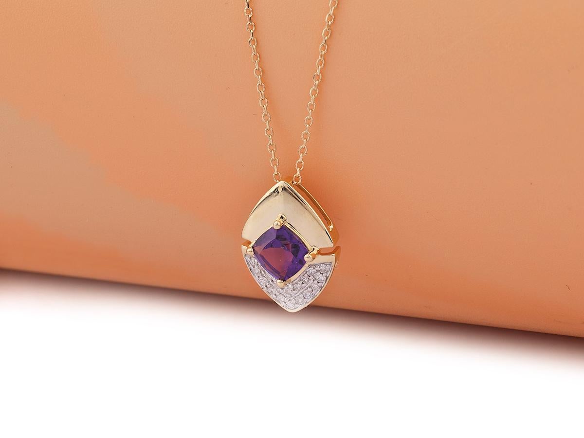 La suspension présente un design géométrique moderne et saisissant, semblable à celui d'un bouclier. L'améthyste est placée en évidence au centre, dans un sertissage sûr, entouré par le travail du métal. La partie inférieure du modèle présente des