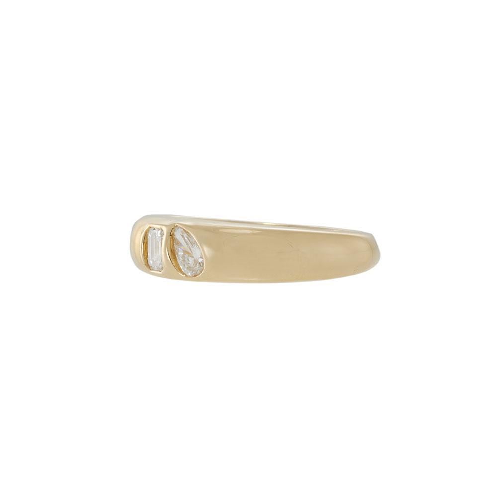 A refined take on modern minimalism. This 14KT yellow gold band features an elegant pairing of bezel-set diamonds — one pear cut, one emerald cut — for a look that feels both unexpected and enduring. The smooth, rounded silhouette adds to its quiet