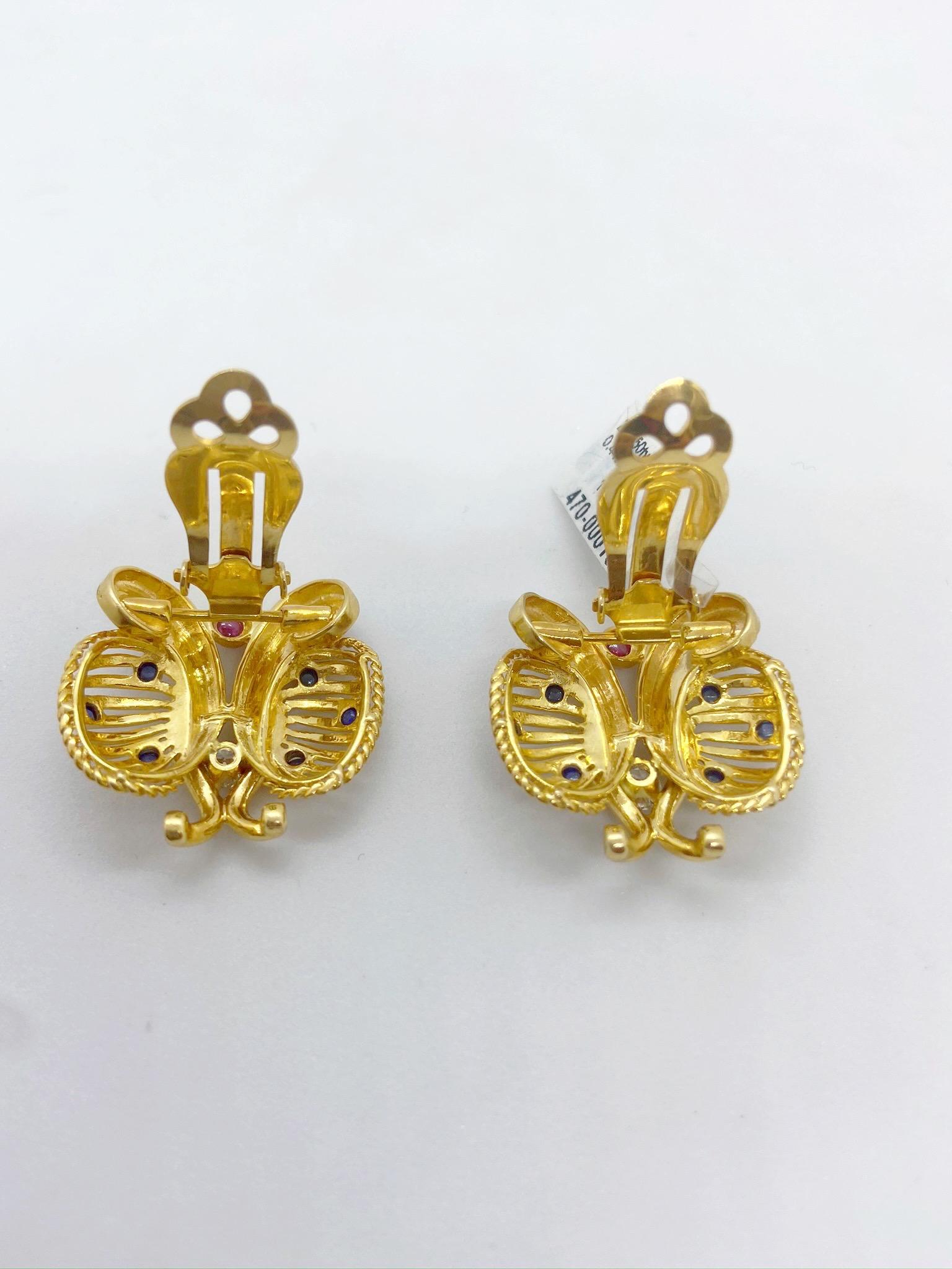 Retro styled 14 karat yellow gold earrings .The Butterfly shaped earrings feature a Round Brilliant Diamond Solitaire in each along with Cabochon Ruby and Blue Sapphires.The clip on earrings measure 7/8