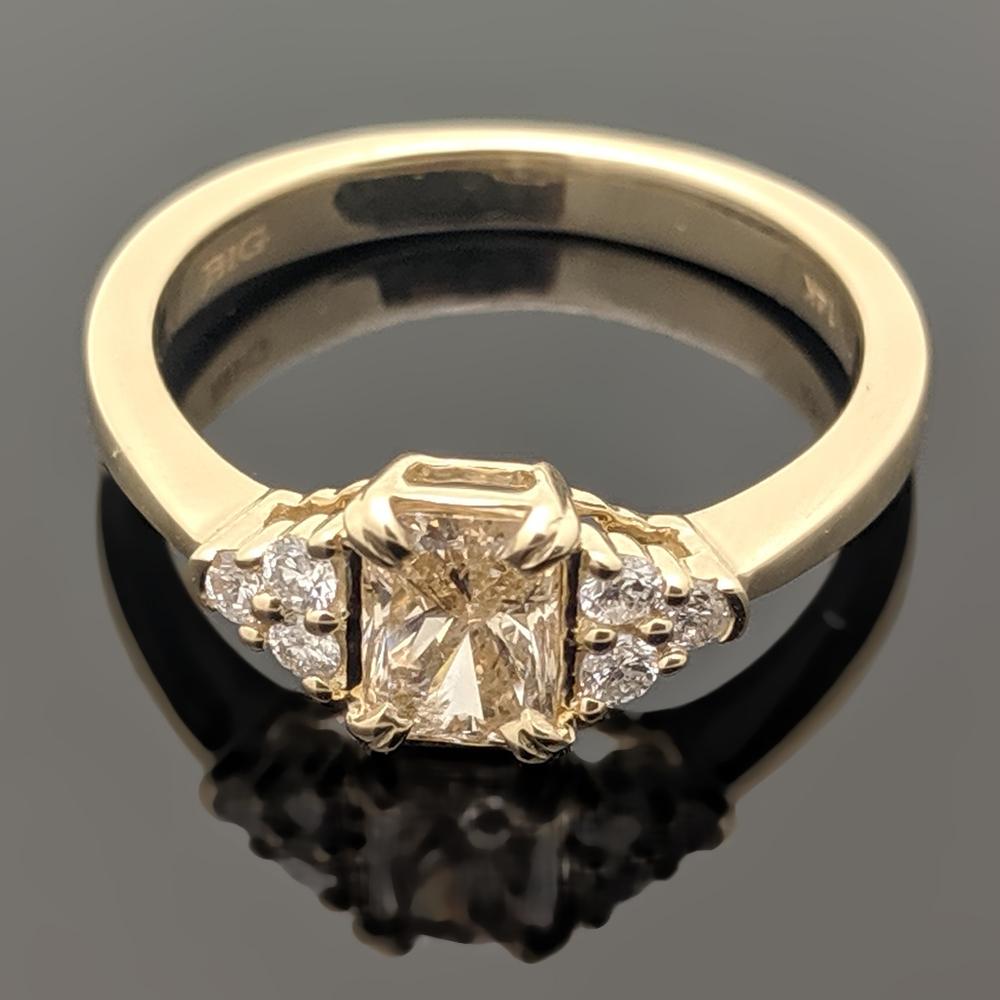 This is an elegant 14kt yellow gold ring with an emerald-cut champagne diamond estimated at 0.63ct and a total of six brilliant cut diamonds at an estimated 0.15cttw.  Estimated weight of gold is 2 gr. 

We will size it for you.

