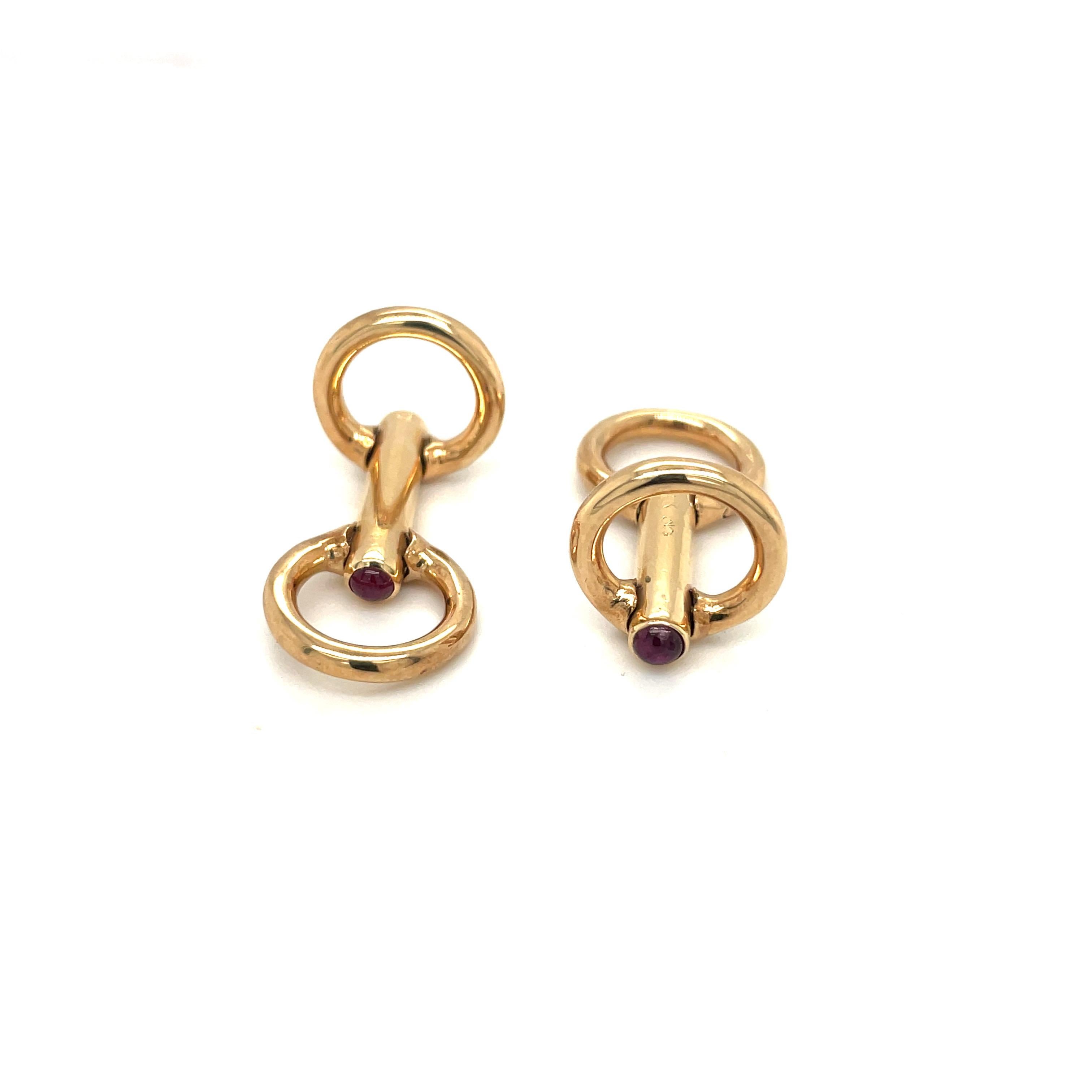 Classic 18 karat yellow gold bar style cuff links. The cuff links are designed with 2 flexible gold circles on each end, tipped with ruby cabochons. They measure 1.25