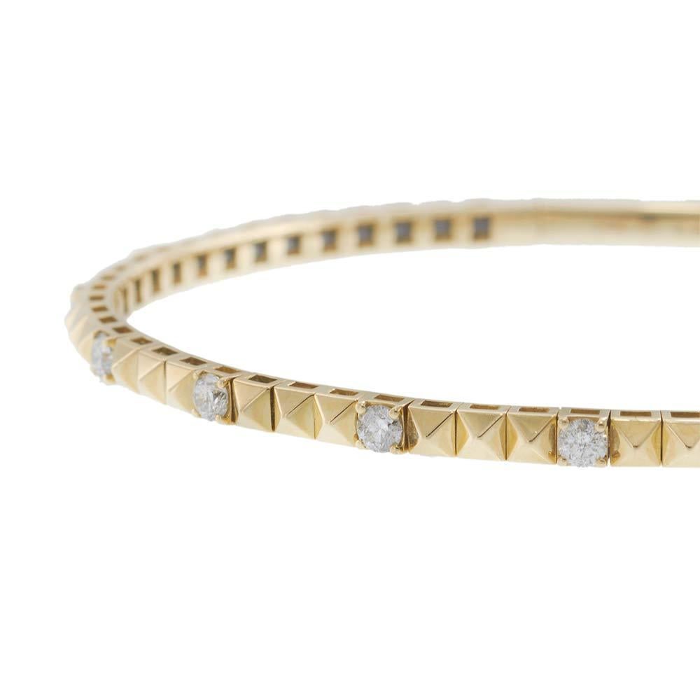 A refined blend of texture and sparkle, this 14KT yellow gold flex bangle features a distinctive pyramid-textured design accented with round brilliant diamonds. Each diamond is spaced evenly around the bracelet, creating a rhythmic pattern of light