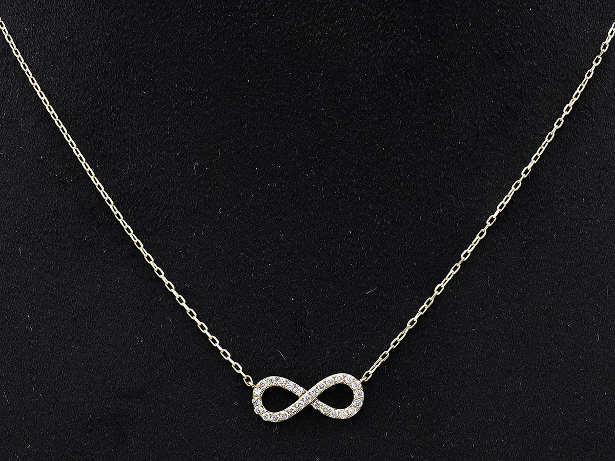 Le pendentif présente l'élégant symbole du huit couché à l'horizontale, ou lemniscate, qui représente quelque chose qui n'a ni début ni fin. La surface du symbole est recouverte de petits diamants ronds sertis en pavé qui maximisent l'éclat et la