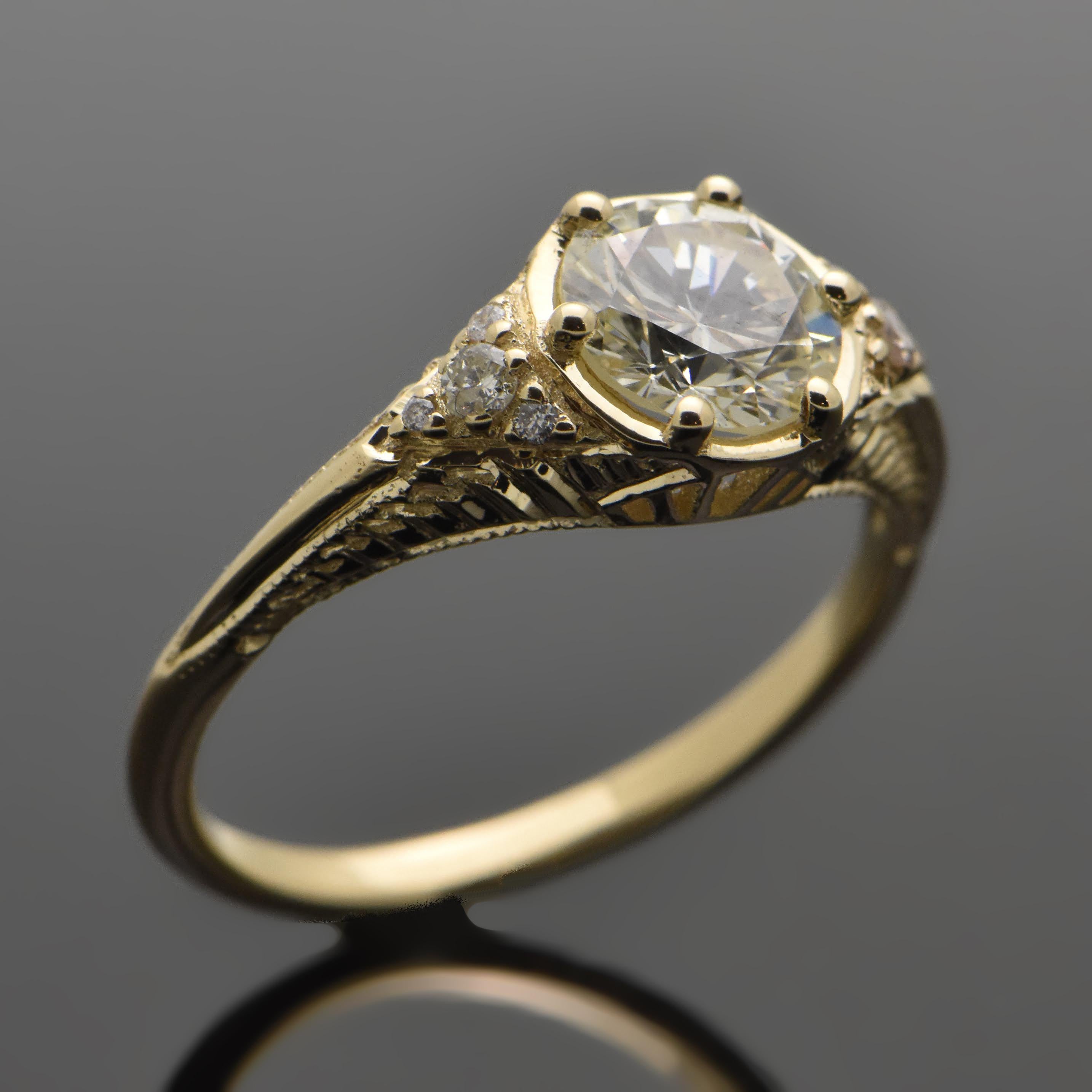 14kt Yellow Gold Diamond Ring. This ring features a round brilliant cut diamond set with 6 prongs, diamond accents on shoulders, and a carved band design. 

This item is a custom order only. Price is for the ring setting only. The stones will be