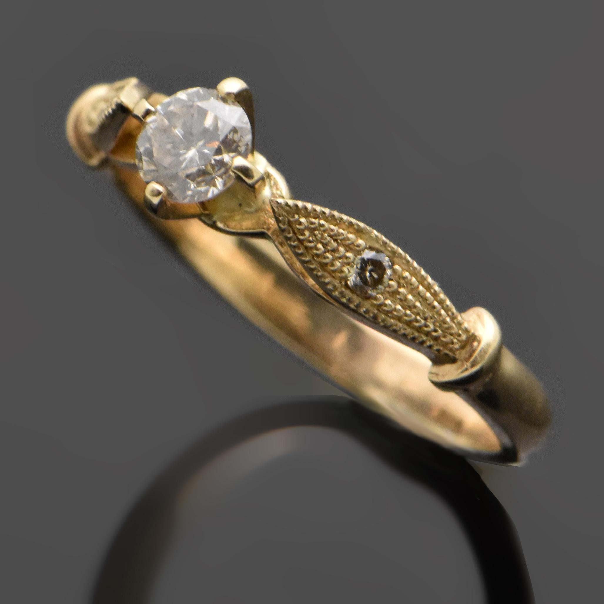 A 14kt yellow gold ring featuring a diamond estimated at 0.30ct. The shoulders are raised into a leaf-like design with beautiful milgran details and diamond accents.   Estimated weight of gold is 2 gr. 

We will size it for you.

