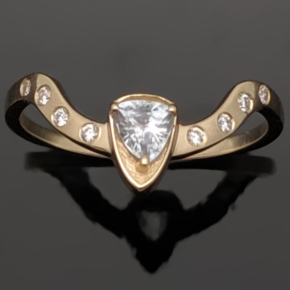 This is a 14kt Yellow Gold Diamonds Ring set with a trillion cut diamond in a shield-shaped gold setting. The band features a wavelike-shape and 8 total accent diamonds. 

This item is a custom order only. Price is for the ring setting only. The
