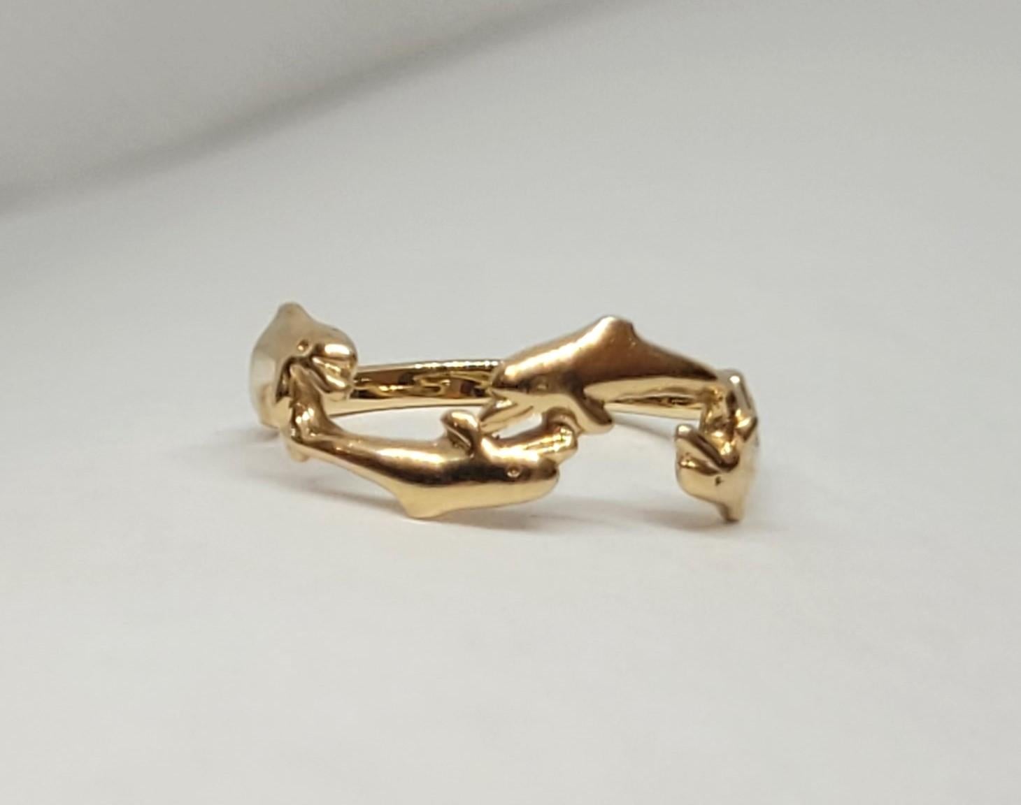 Ring aus 14-karätigem Gelbgold mit vier springenden Delphinen, die über den oberen Teil des Fingers verlaufen. Der Ring ist an der breitesten Stelle 6,5 mm breit und verjüngt sich an der Basis auf 1,8 mm. Er wiegt 1,7 Gramm, ist mit 14kt gestempelt