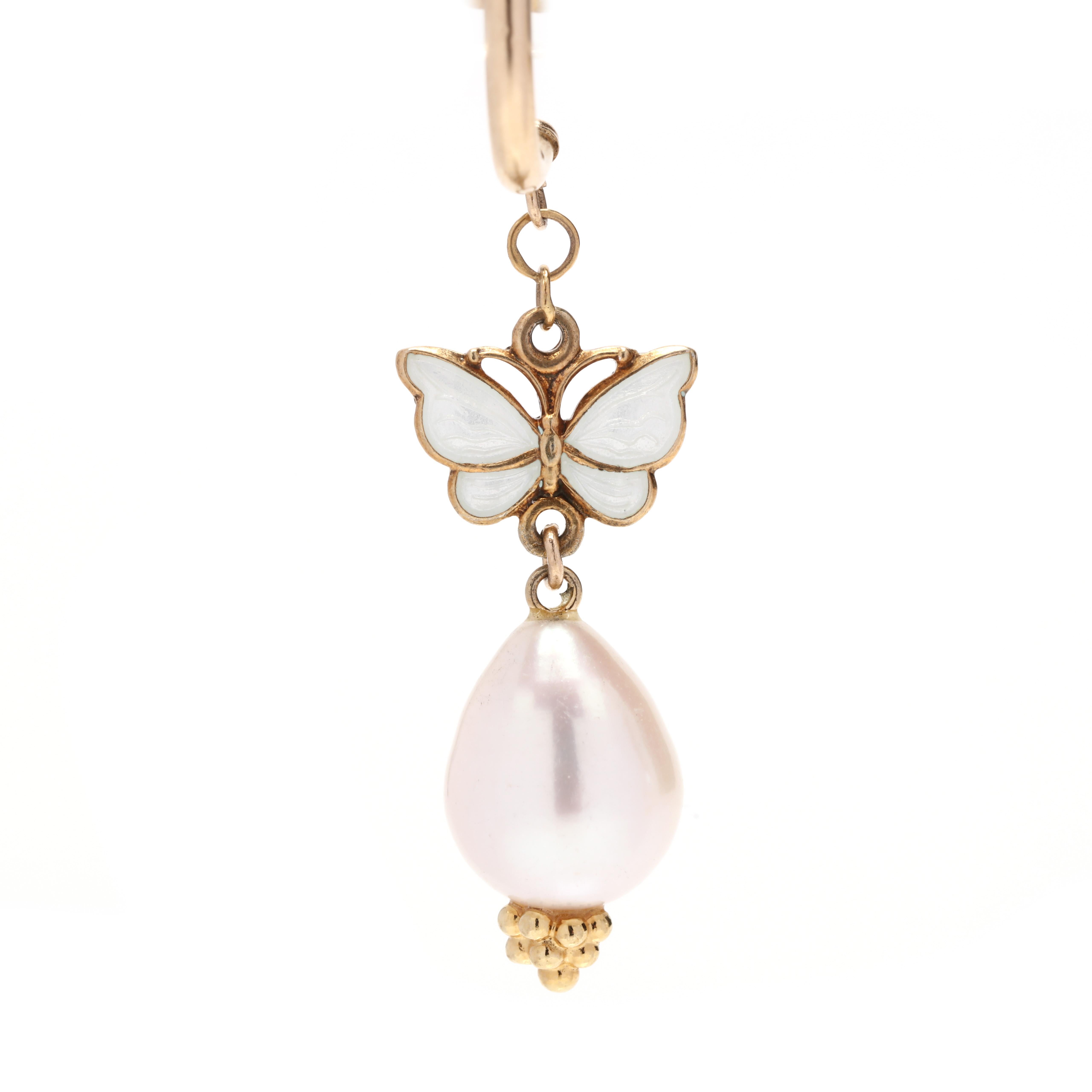 A pair of 14 karat yellow gold enamel butterfly and pearl dangle earrings. These earrings feature a stud, pierced half hoop design suspended a butterfly motif with white enamel detailing and an oblong pearl with beaded detailing