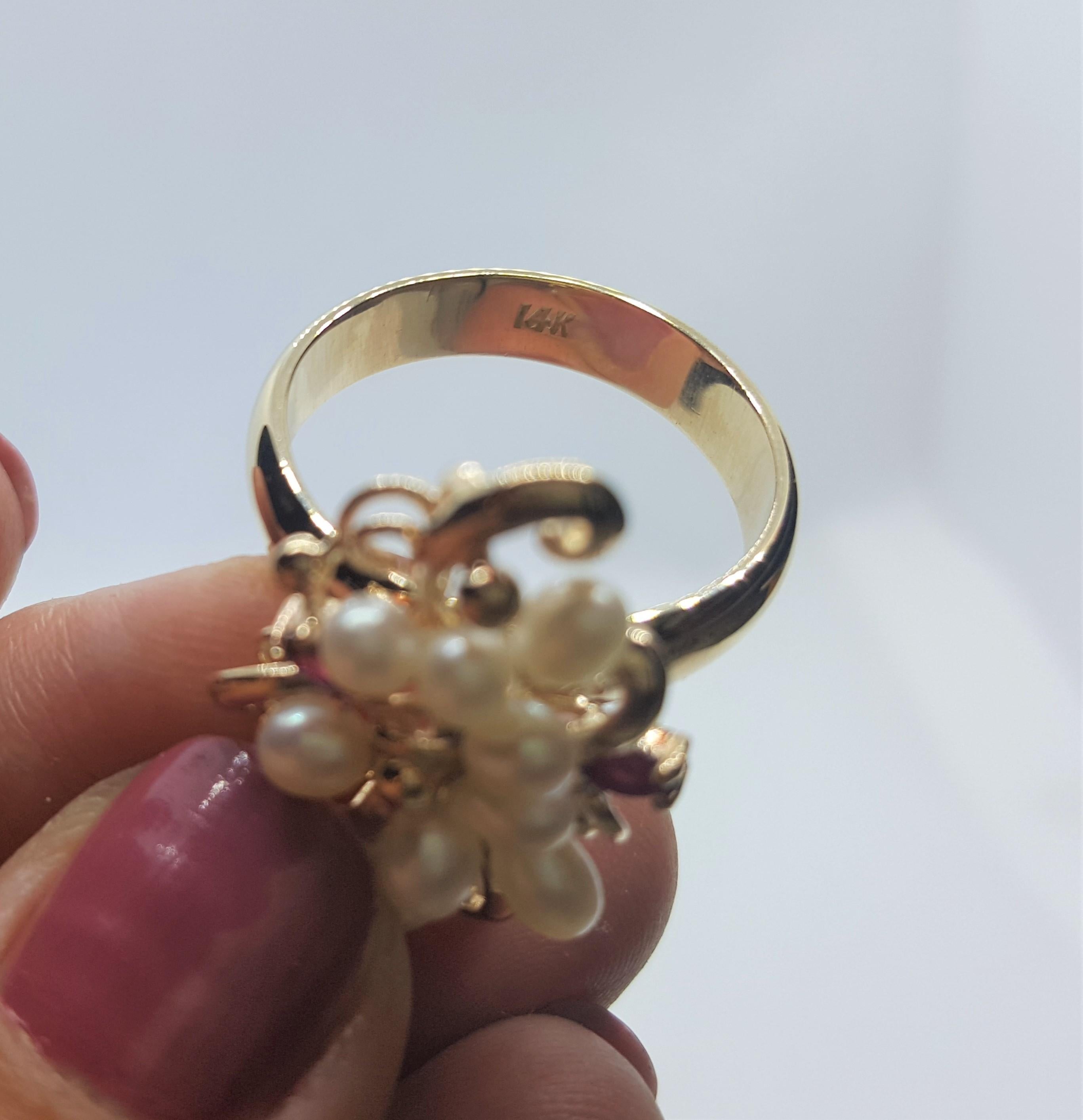 Unique 14kt yellow gold ring with 12 freshwater white pearls, 2 marquis-shaped rubies of approximately .06cttw. The pearls are in very good condition with clean lustrous nacre. The ring is 10.25 in size but it can be sized; the ring weighs 9.3 grams