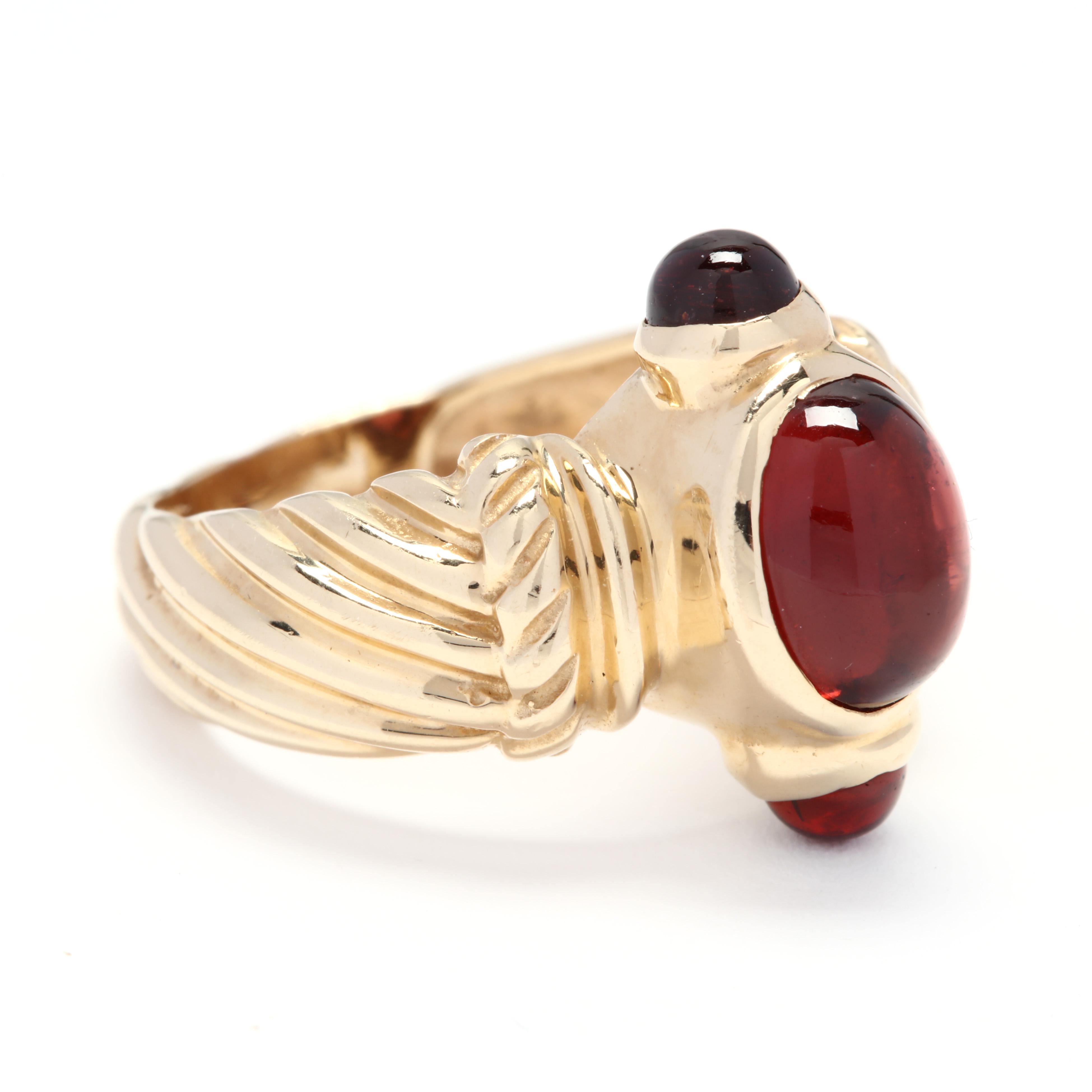 A 14 karat yellow gold and garnet cable ring. Centered on a bezel set, oval cabochon garnet stone with a bezel set, round cabochon garnet on each side of the profile and a tapered, cable motif shank. 

Stones:
- garnets, 3 stones
- oval cabochon
-