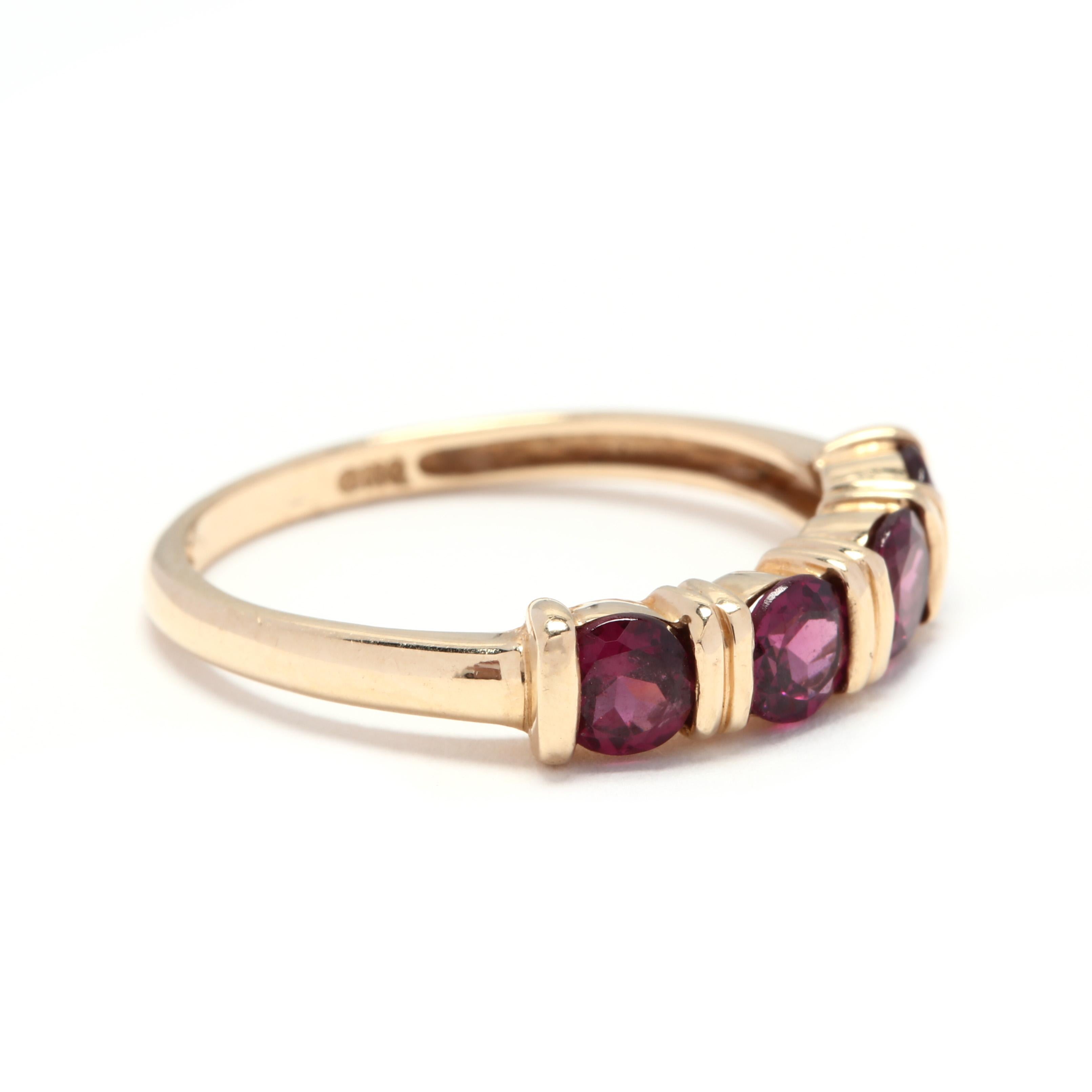 A 14 karat yellow gold and garnet stackable band. A minimalist design with four bar set, round cut garnets with ridged designs and a slightly tapered shank.

Stones:
- garnets, 4 stones
- round
- 4 mm
- approximately 1.4 total carats

Ring Size