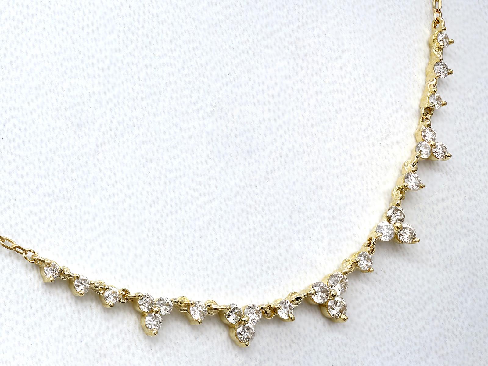 La collana ha un design minimalista ed elegante in cui piccoli diamanti rotondi sono incastonati l'uno vicino all'altro in una leggera curva verso l'alto. I diamanti sono graduati, cioè sono più piccoli alle estremità e più grandi al centro, creando