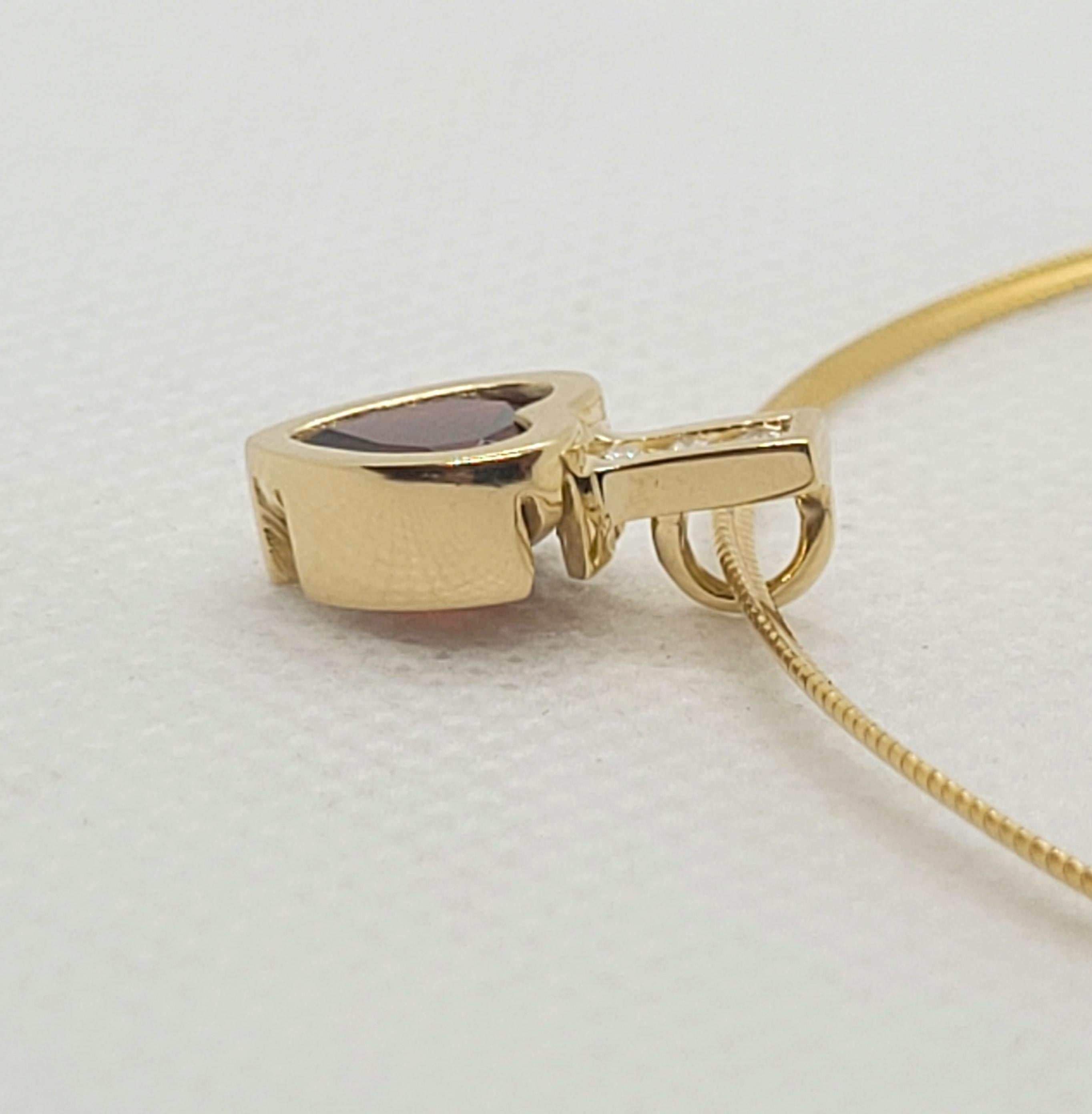 Beautiful 14kt yellow gold pendant with a heart-shaped garnet gemstone accented with 3 round brilliant diamonds of approximately .07cttw.  The garnet and diamonds are in very good condition and this pendant appears hardly worn; the diamond quality