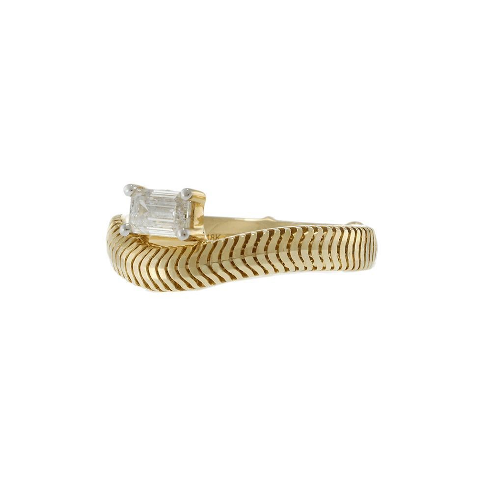 Une bague architecturale élégante conçue pour captiver avec une sophistication subtile. Réalisé en or jaune 14KT, ce bracelet présente un motif à chevrons complexe qui s'enroule autour du doigt avec une courbe distinctive. Au centre, un diamant de