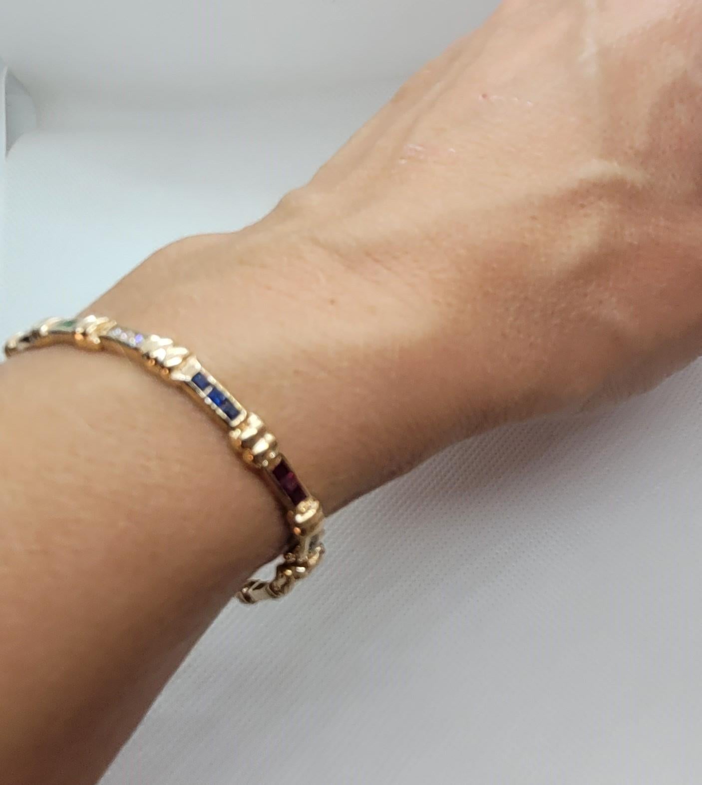 Dieses wunderschöne Armband im Tennisstil ist aus 14-karätigem Gelbgold gefertigt und mit Diamanten im Prinzessinnenschliff, Saphiren, Rubinen und Smaragden besetzt. Es umfasst neun Diamanten mit einem Gesamtgewicht von etwa 0,40 Karat, zwölf