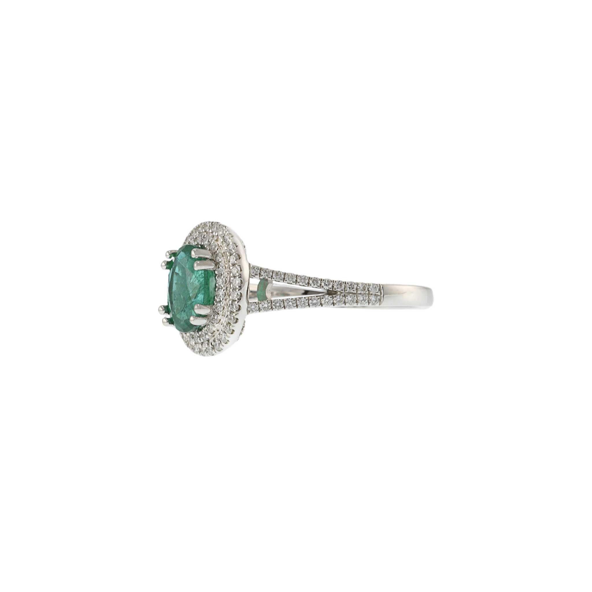This elegant ring features a 1.20 carat oval cut emerald, beautifully set in 14KT yellow gold. The vibrant emerald is surrounded by a double halo of 0.40 carats of round cut diamonds, adding a touch of sparkle and sophistication. This exquisite